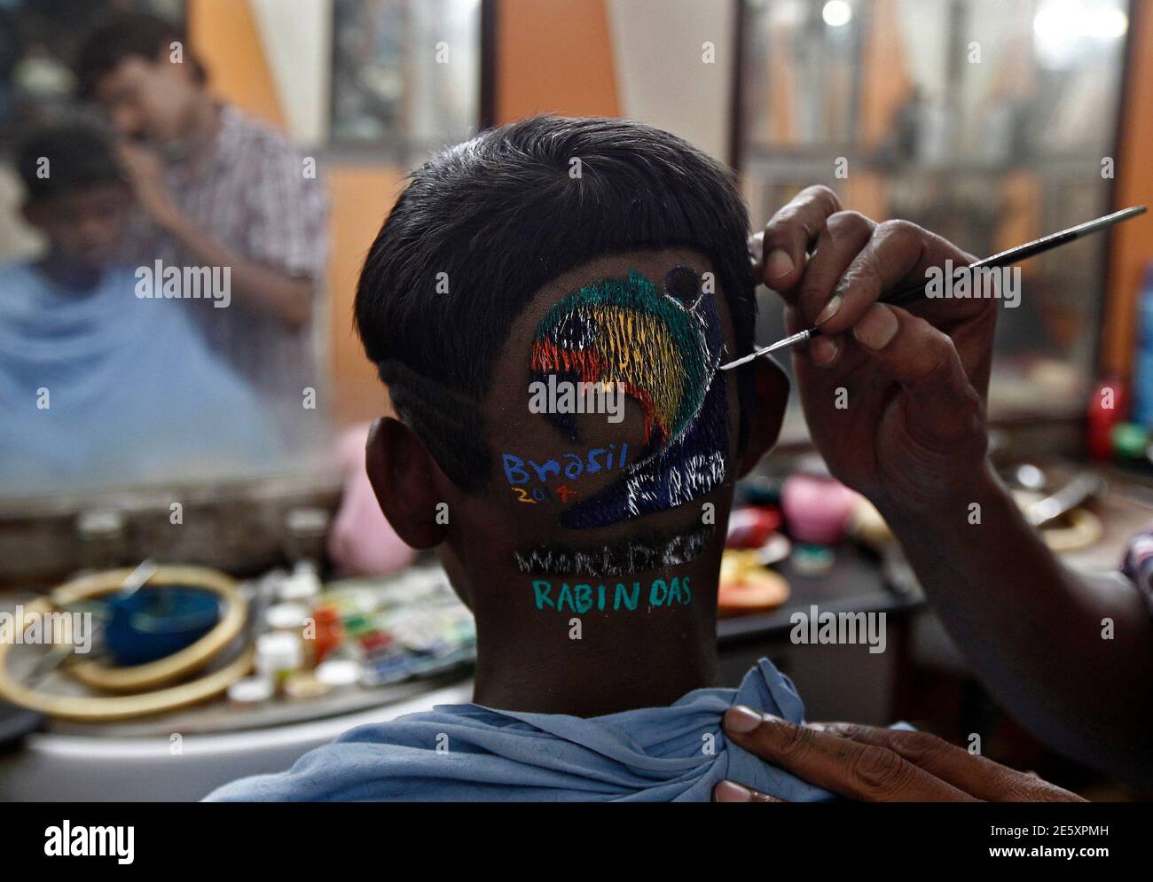 Indian hair stylist Rabin Das applies colour on the hair of a soccer fan  after the haircut inside his saloon on the outskirts of Kolkata, ahead of  the 2014 World Cup in