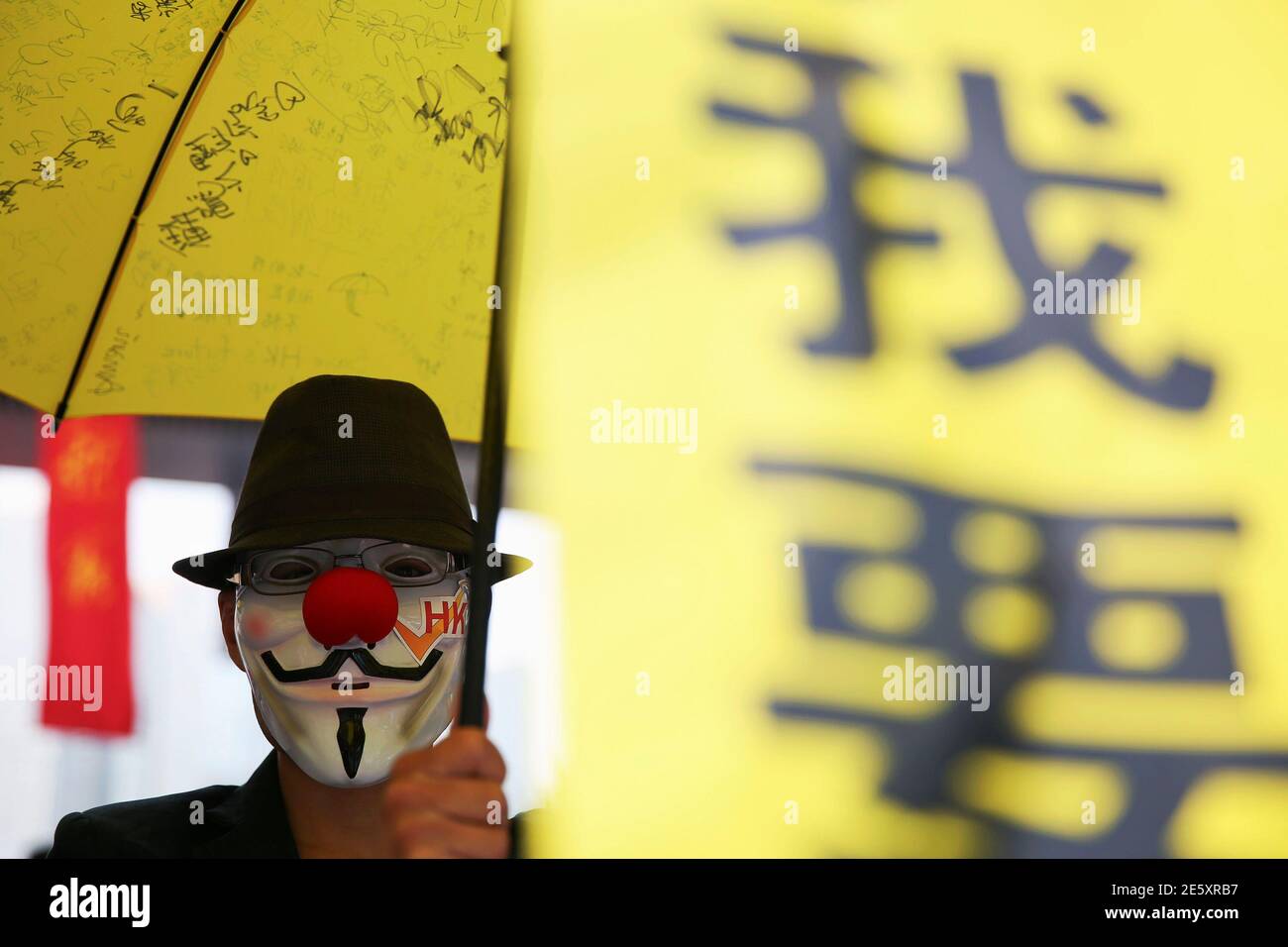 A pro-democracy protester wearing a Guy Fawkes mask holds a yellow umbrella and a banner in the part of Hong Kong's financial central district protesters are occupying November 2, 2014. The former British colony of Hong Kong, which returned to Chinese rule in 1997, has witnessed a month of protests calling on the Beijing-backed government to keep its promise of introducing universal suffrage. The protests have for the most part been peaceful, with occasional clashes between the student-led protesters and Beijing supporters seeking to move them from the streets.   REUTERS/Damir Sagolj (CHINA -  Stock Photo