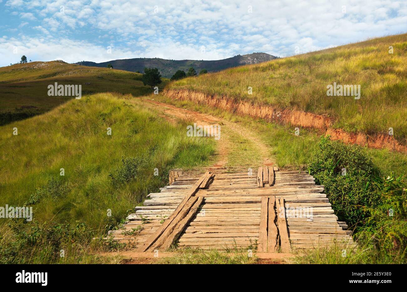 Bridge made of wooden bars on country road, grass growing on hills both sides - typical view when driving 4wd off road vehicle near Andringitra park, Stock Photo