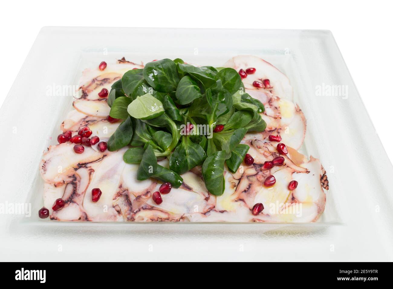 Carpaccio octopus with shpinach in a white plate. It is located in a white background. Close-up. Stock Photo