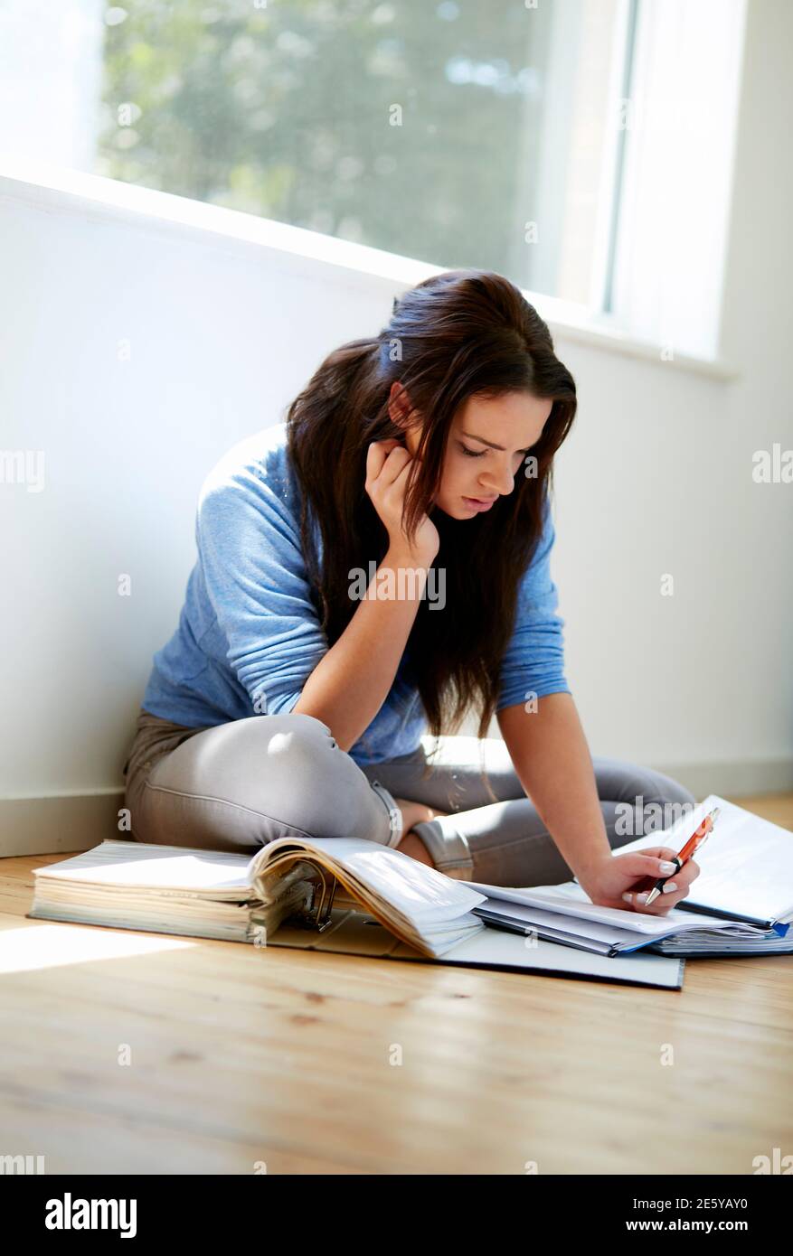 Student girl sat on the floor studying Stock Photo