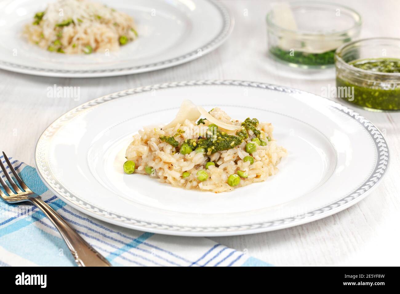 Homemade risotto with green peas, parmesan and pesto on a white plate