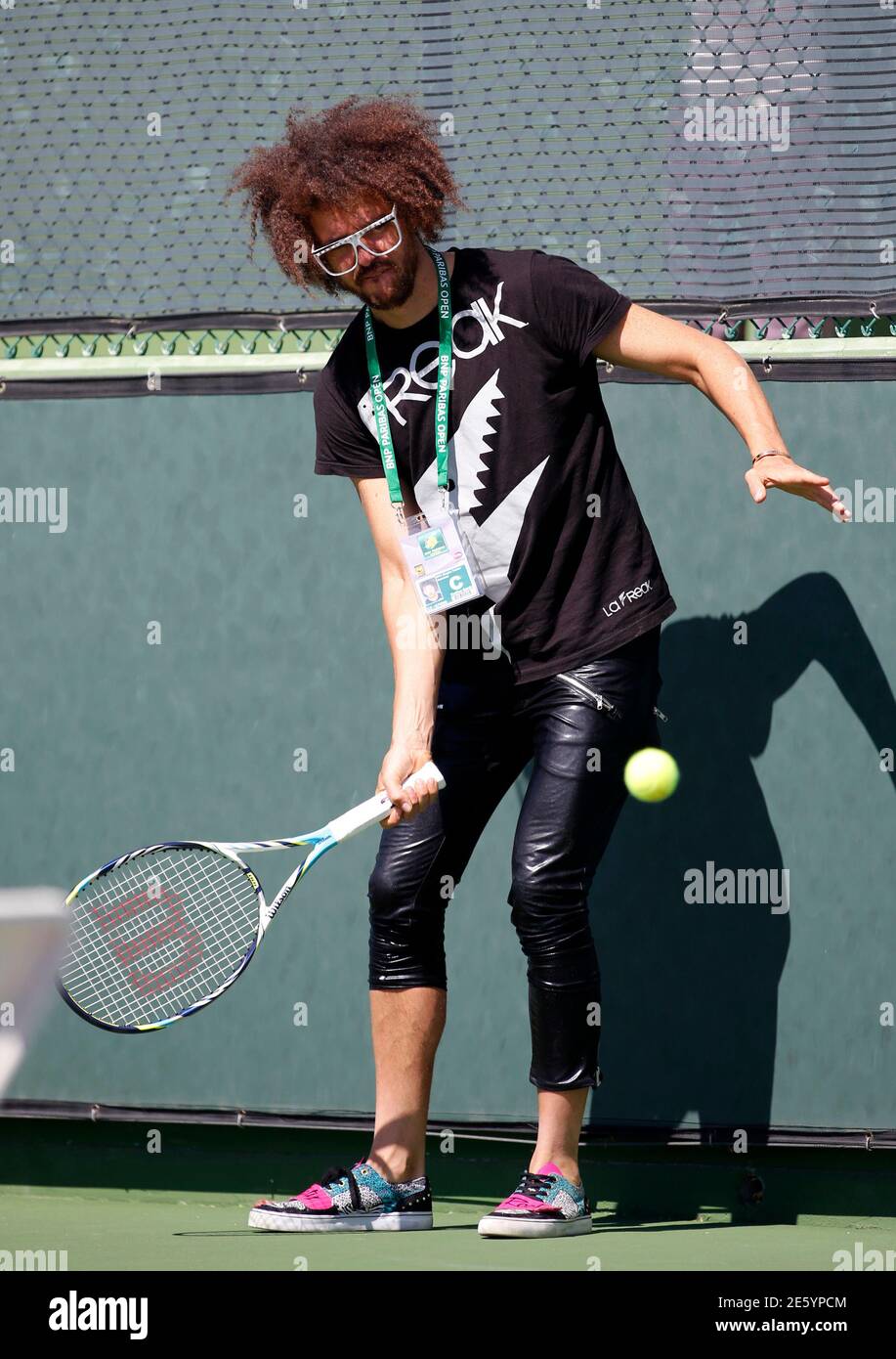Redfoo, also known as Stefan Gordy of the band LMFAO, hits a tennis ball as  his girlfriend Victoria Azarenka of Belarus attends a practice session to  prepare for the BNP Paribas Open