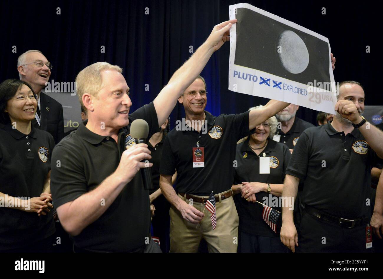 NASA Principal Investigator for New Horizons mission Alan Stern (L) and Co-Investigator Will Grundy (R) hold up an enlarged, out-dated U.S. postage stamp with the 'NOT YET' crossed out, during the celebration of the spacecraft New Horizons flyby of Pluto, at NASA's Johns Hopkins Applied Physics Laboratory in Laurel, Maryland, July 14, 2015. The flyby, which culminated after almost ten years of flight and over three billion miles, will allow New Horizons to photograph and collect data in the coming months.                            REUTERS/Mike Theiler      TPX IMAGES OF THE DAY Stock Photo