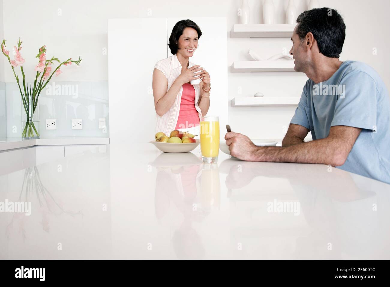 Happy couple having breakfast at kitchen bench Stock Photo