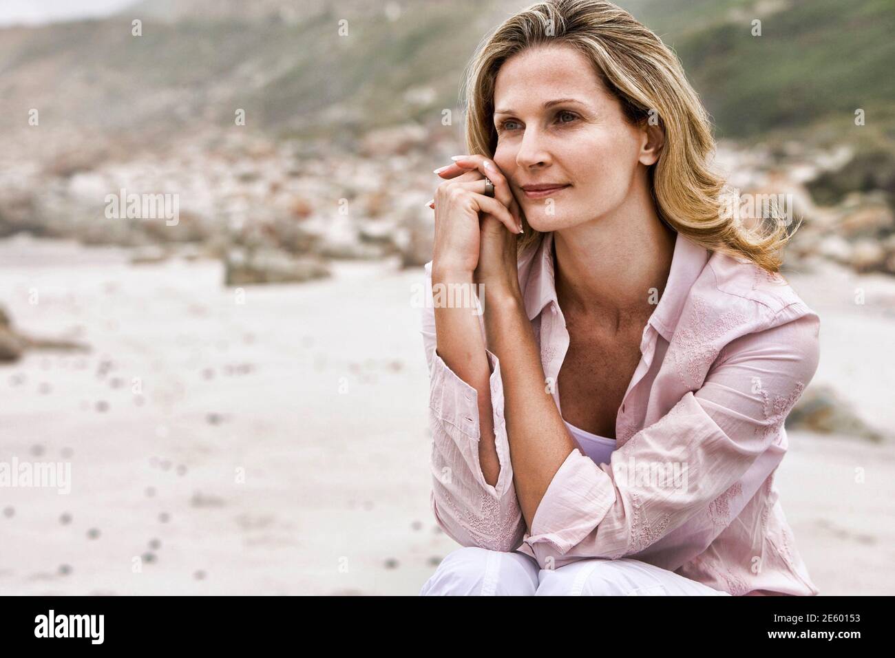 Beautiful woman daydreaming while relaxing at beach Stock Photo