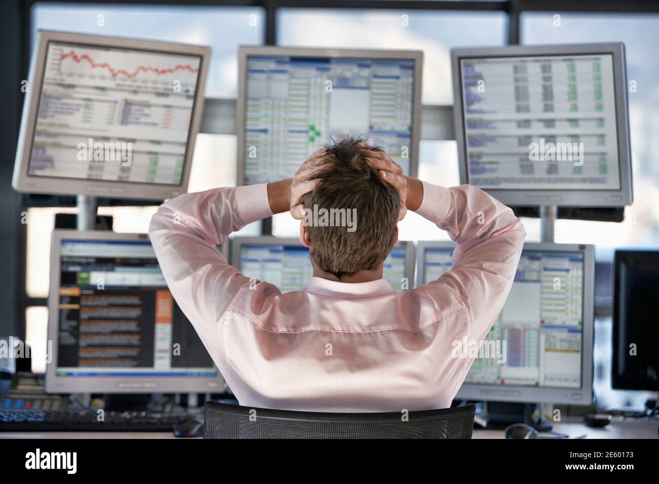Rear view of stressed stock trader looking on computer screens Stock Photo