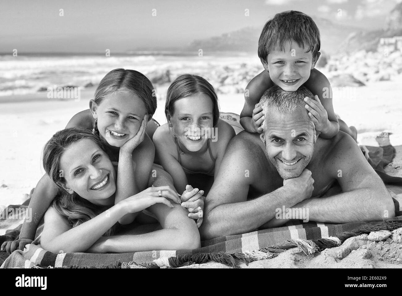 Black and white photo of happy family lying on the beach Stock Photo