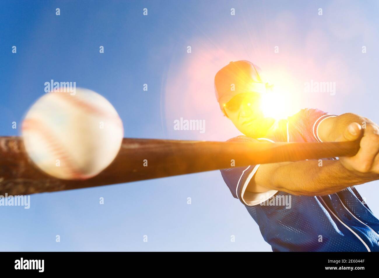 Batter Hitting Baseball on sunny day Stock Photo
