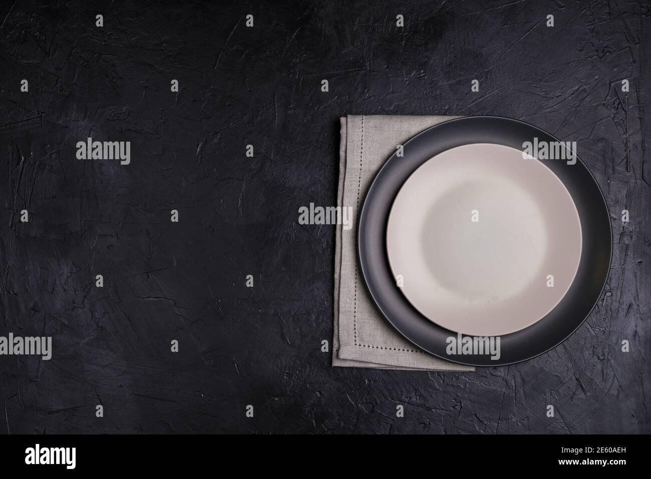 https://c8.alamy.com/comp/2E60AEH/black-and-light-plates-linen-napkin-on-black-stone-table-top-view-table-setting-2E60AEH.jpg