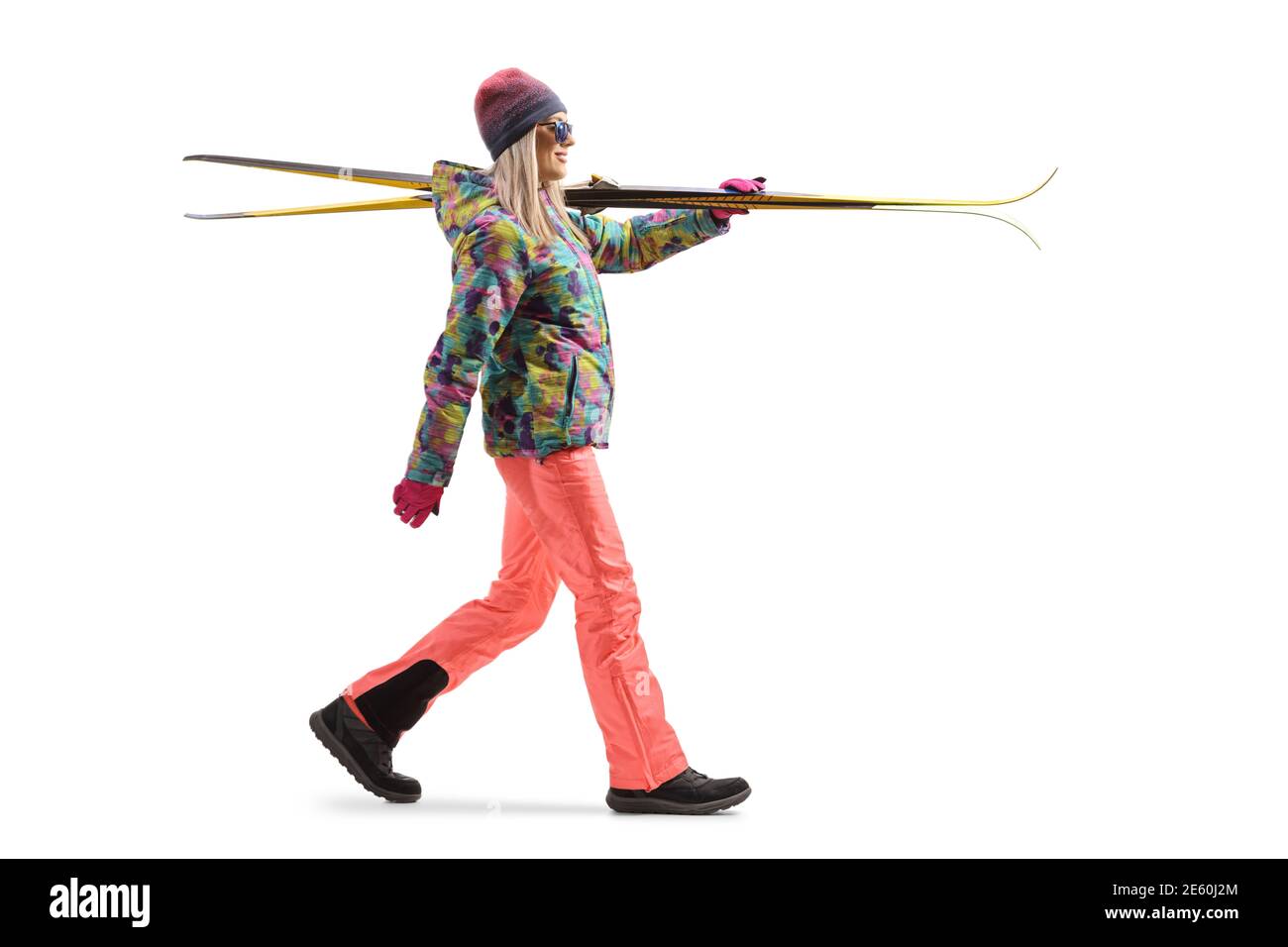 Full length profile shot of a woman walking and carrying skis isolated on a white background Stock Photo