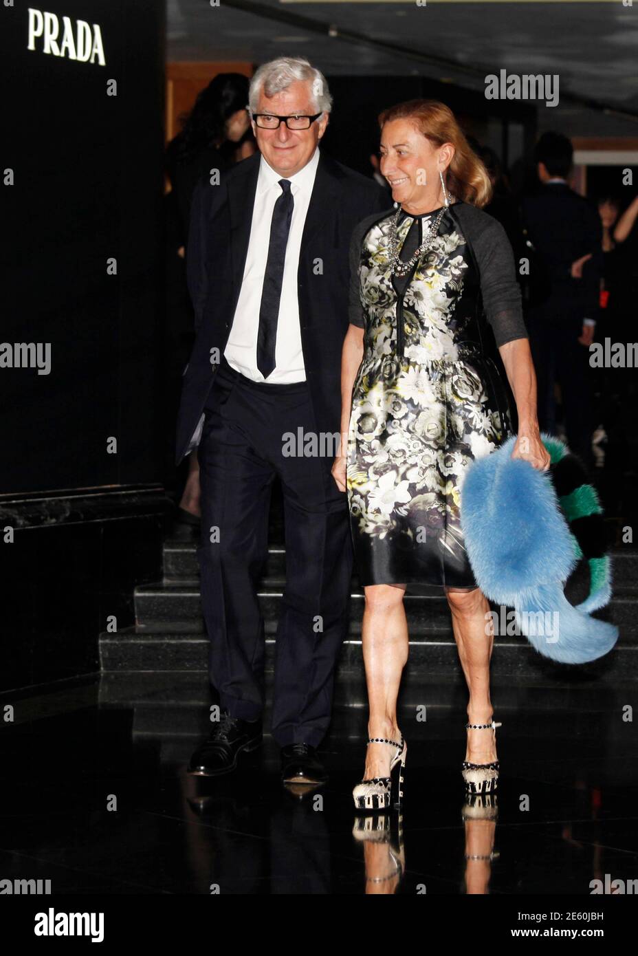 Italian fashion designer Miuccia Prada and her husband Patrizio Bertelli,  also Prada's chief executive, walk past a Prada logo during an investors  launching presentation ahead of Prada's IPO in Hong Kong June