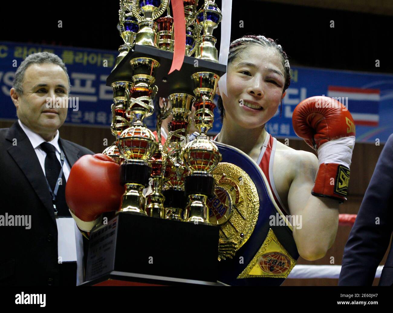 Kim Ju-hee of South Korea, holding a trophy and wearing five champion belts, celebrates her victory against Fahpratan Looksaikongdin of Thailand after their 10-round bout five women's world light flyweight titles