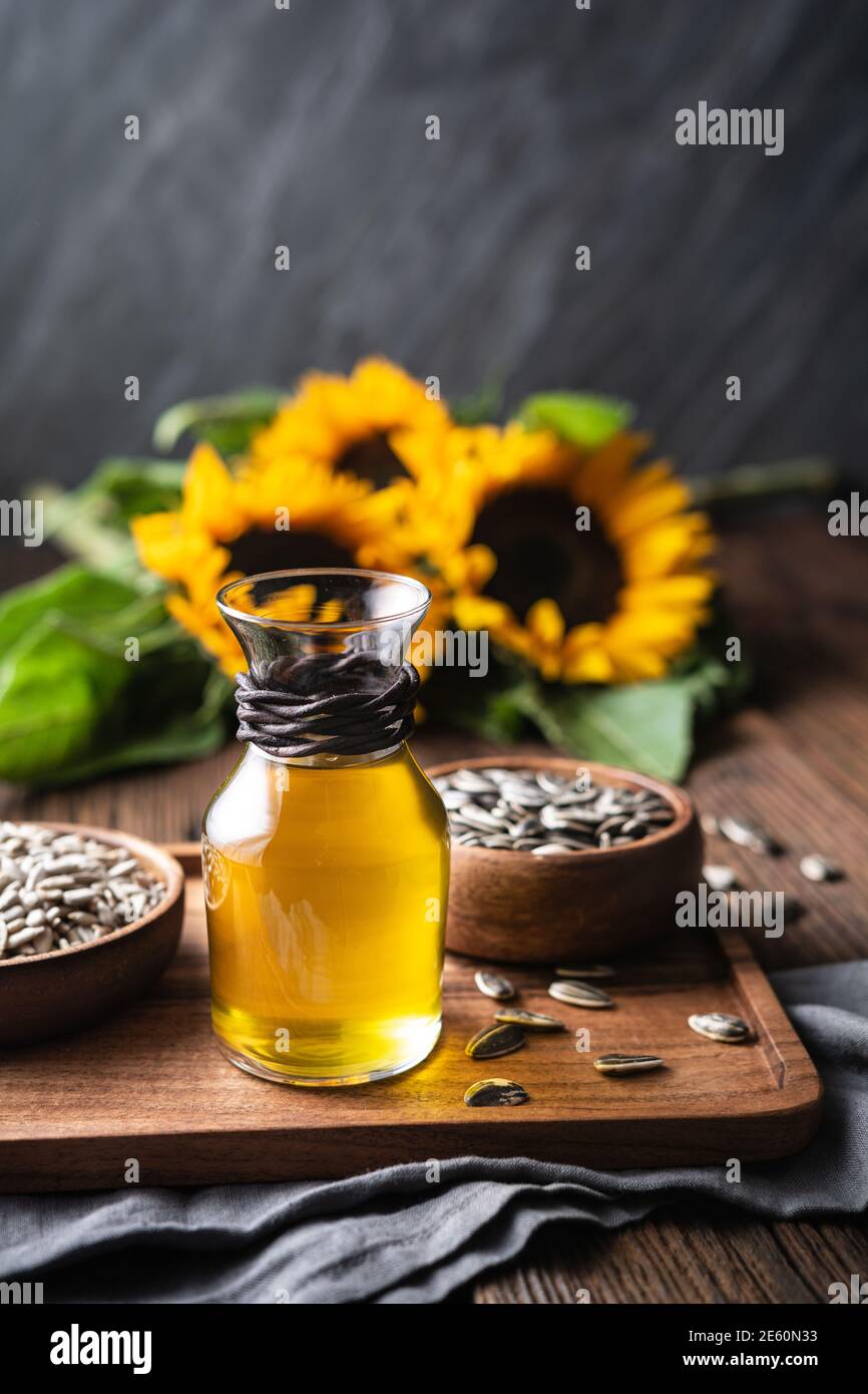 Sunflower oil in a glass jar, decorated with whole seeds and flowers on wooden table Stock Photo