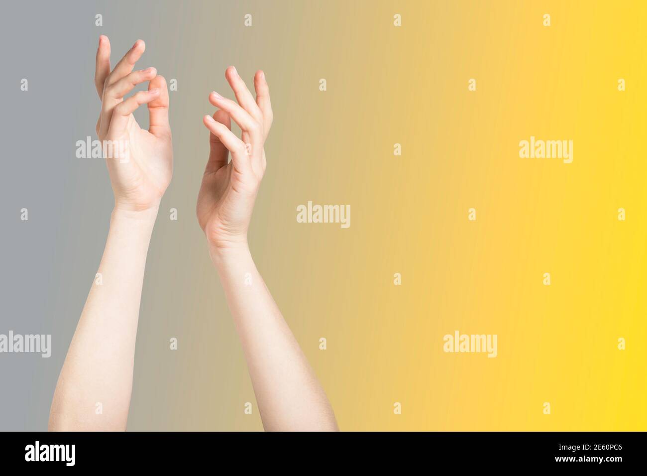 Two hands on the gray and illuminating yellow background treatment concept and empty space Stock Photo