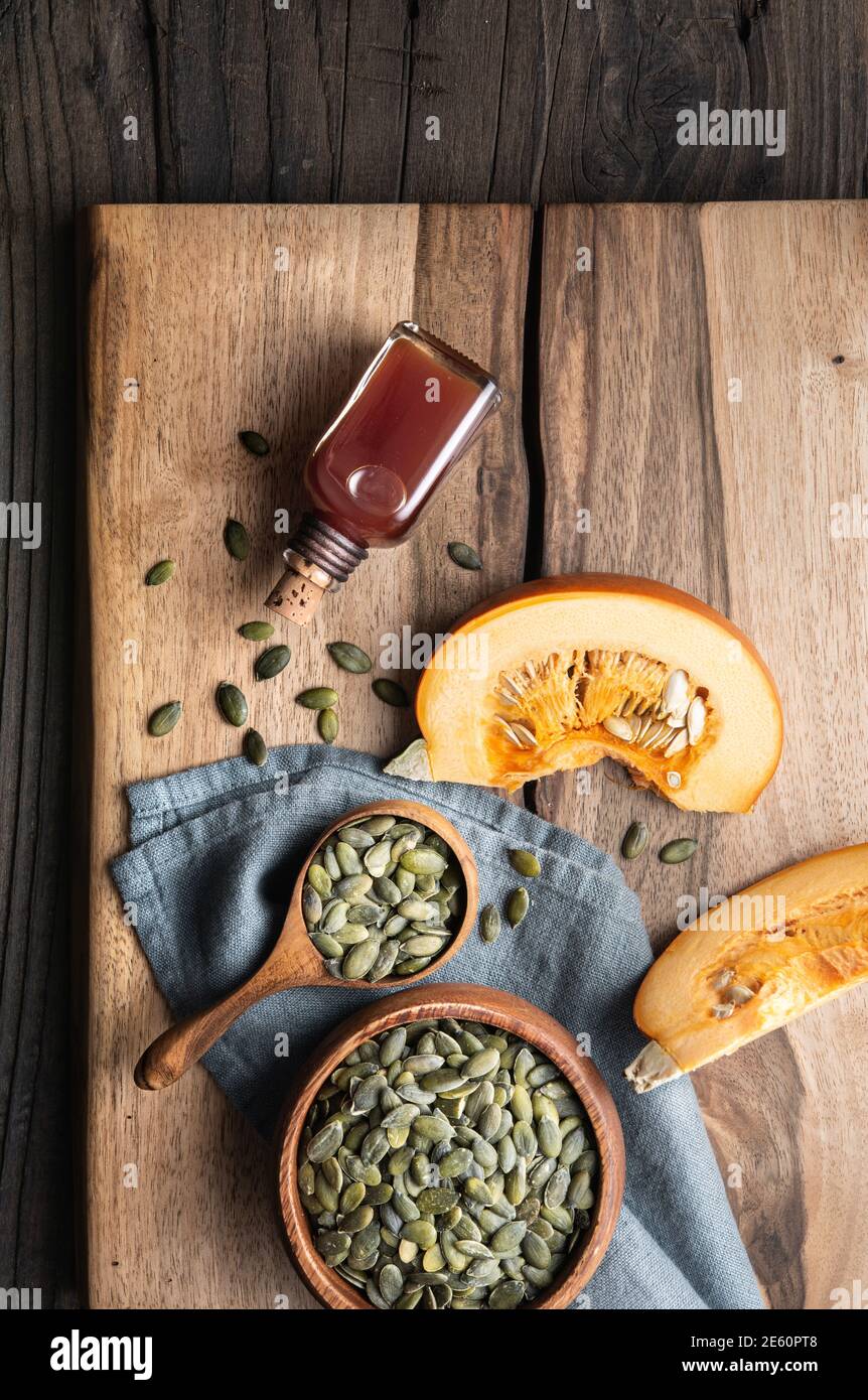 Cold pressed Pumpkin seed oil in a glass bottle, decorated with peeled seeds on wooden table Stock Photo