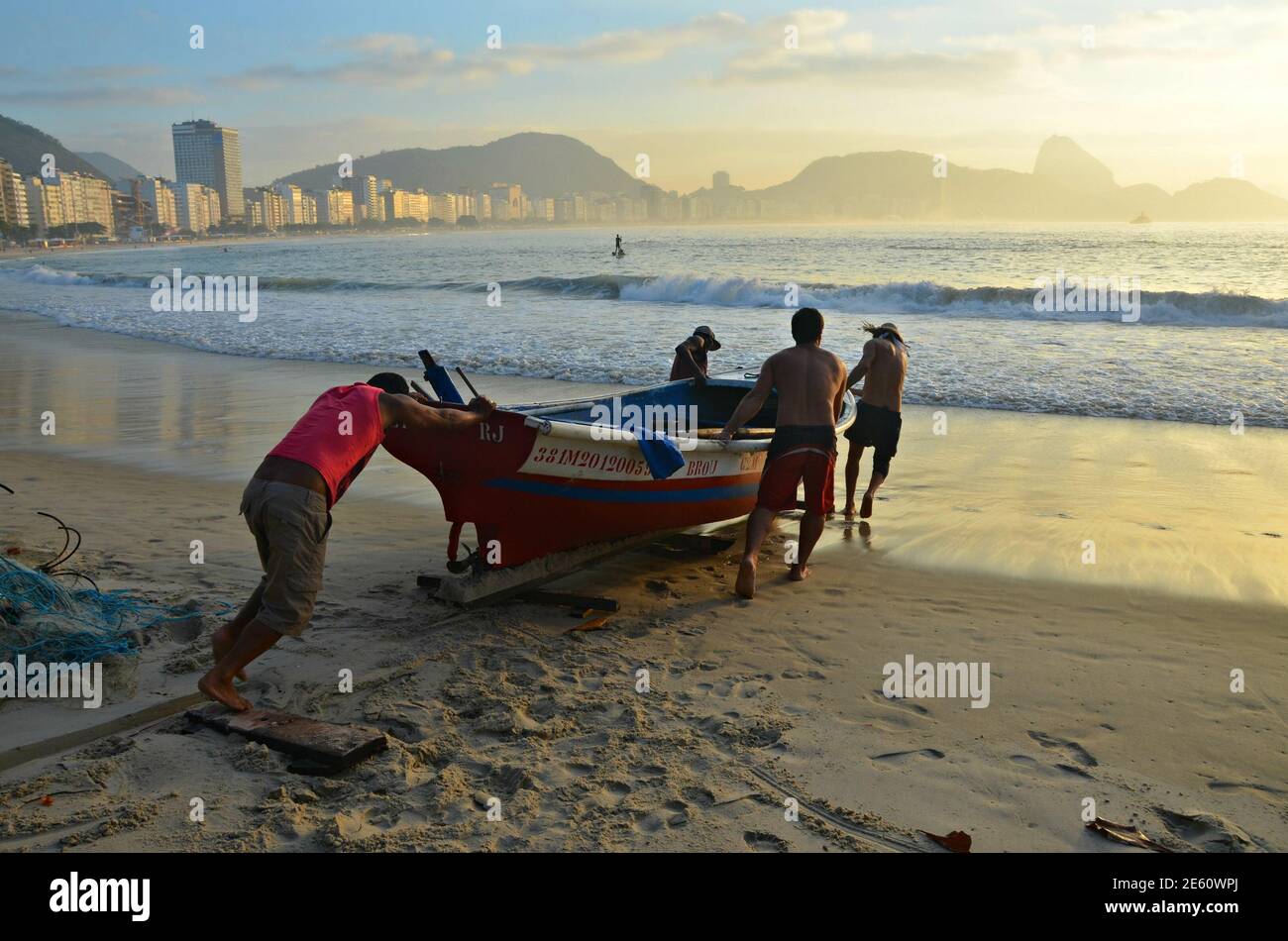 Sunrise seascape with local fishermen and their traditional fishing boat at Colônia dos Pescadores, in Copacabana Beach, Rio de Janeiro Brazil. Stock Photo