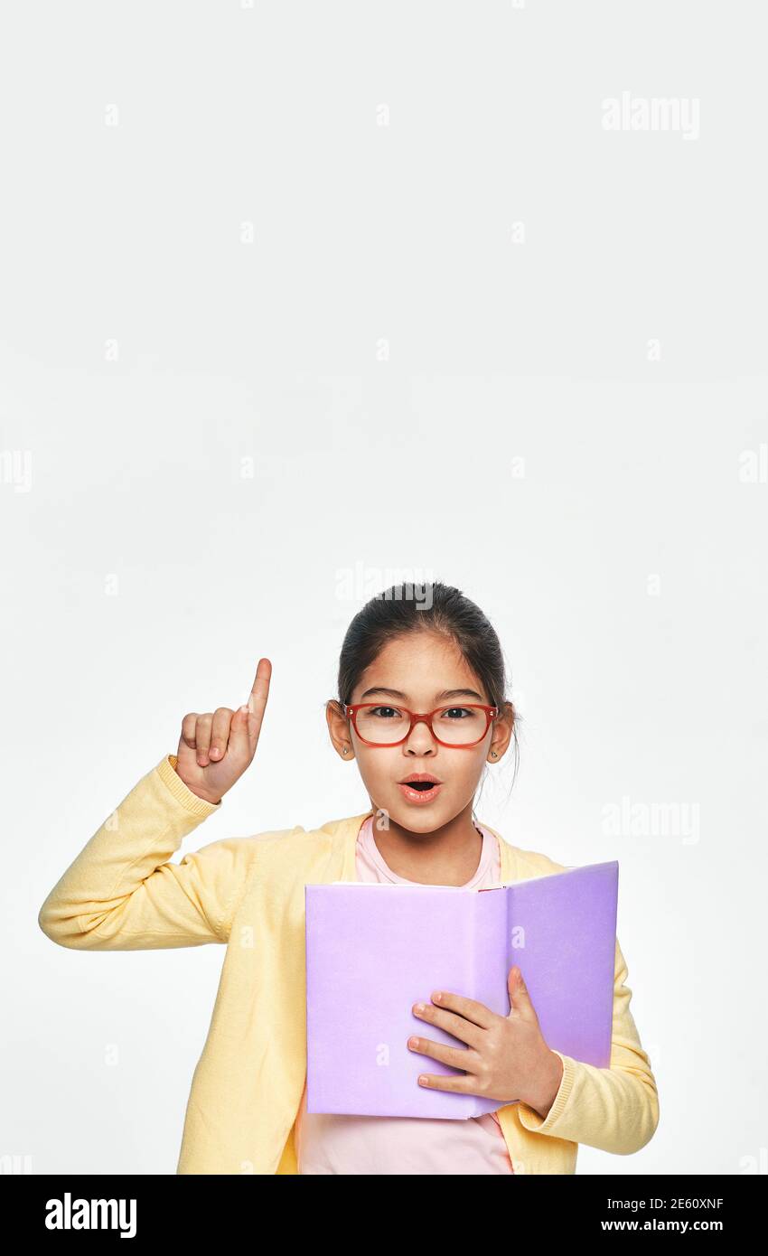 This is a good idea. Asian child with book in hands shows index finger up, on gray background Stock Photo