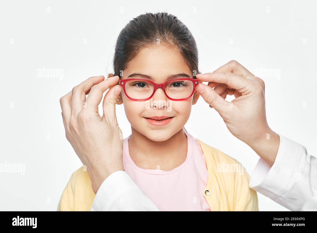 Ophthalmologist tries on eyeglasses of a Latin American little girl
