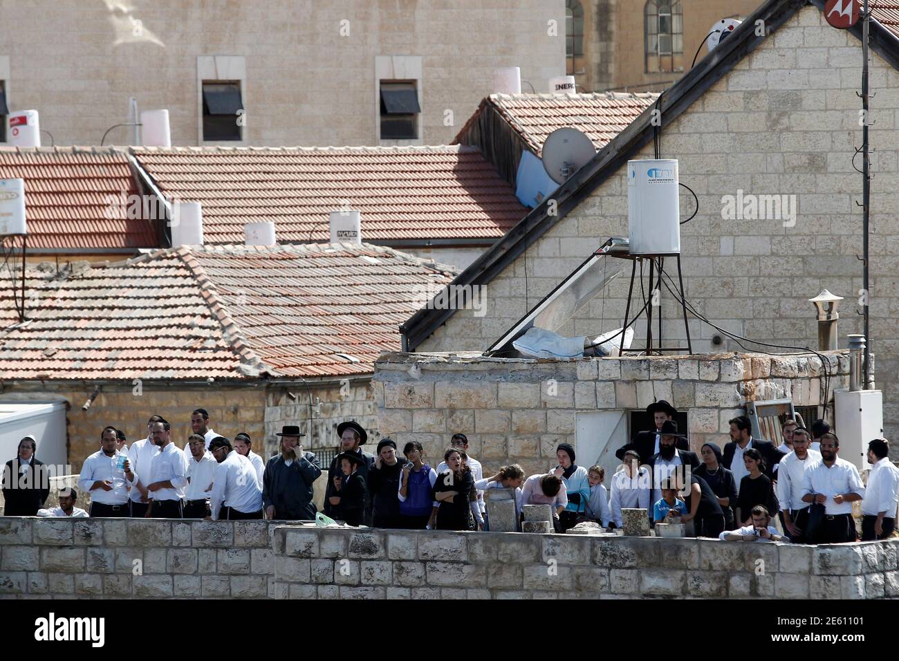 Residents stand on a roof as they observe the scene of a suspected attack in Jerusalem August 4, 2014. A Palestinian used his heavy construction vehicle to run down and kill an Israeli and overturn a bus on a main Jerusalem street on Monday in attacks that ended when policemen shot him dead, police said. REUTERS/Siegfried Modola (JERUSALEM - Tags: POLITICS CIVIL UNREST) Stock Photo