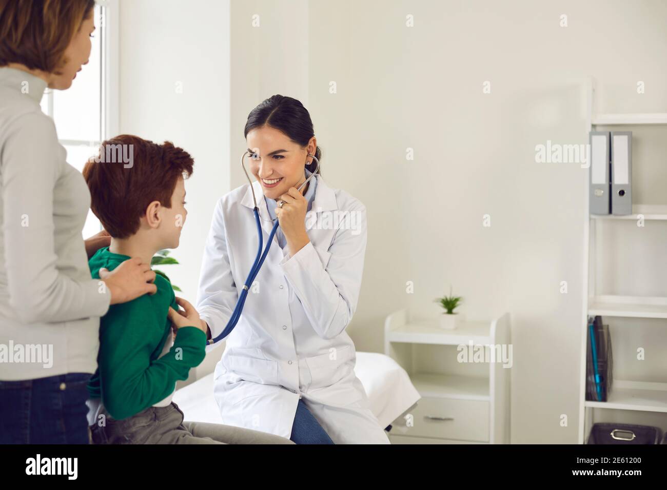 Female pediatrician makes a medical examination and attaches a stethoscope to the baby's chest. Stock Photo