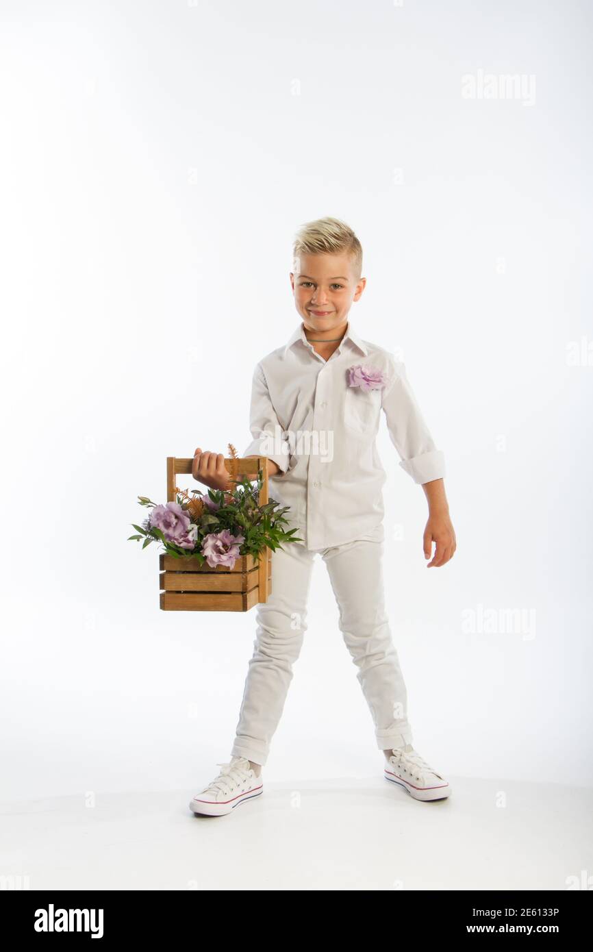 Studio portrait of fashionable blond caucasian boy with wooden basket of flowers, white backdrop, copy space Stock Photo