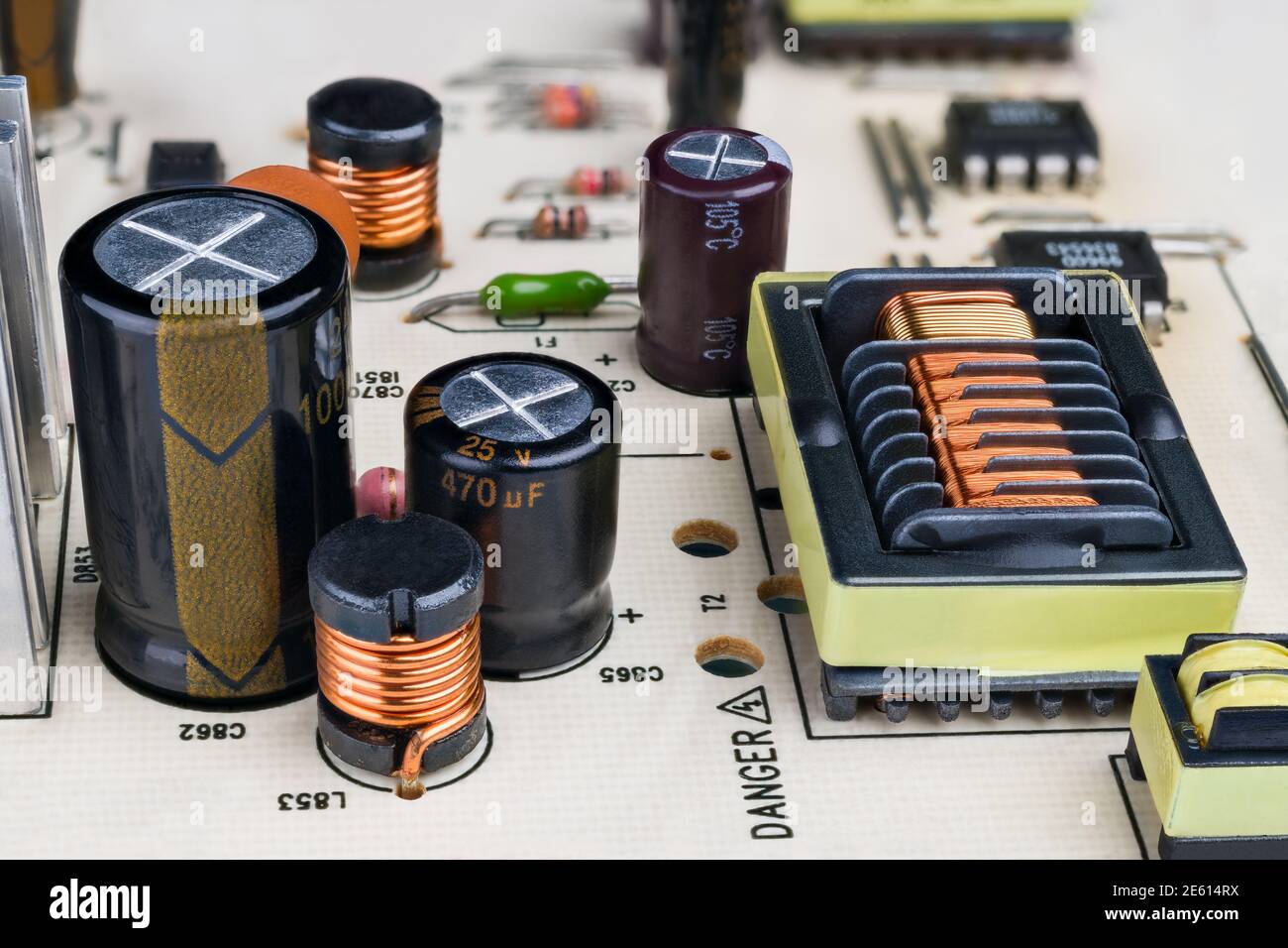 Electronic components on printed circuit board detail. Closeup of capacitors, inductors and rectangular transformer with protruding insulation grooves. Stock Photo