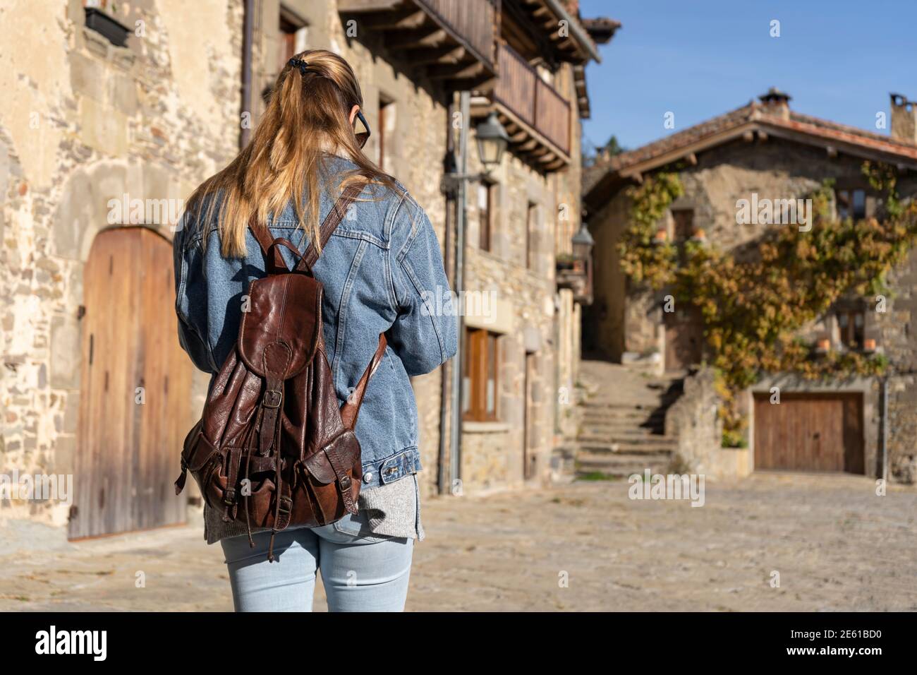 Young woman walking with fashion jeans jacket and backpack in old medieval  village.Back view, travel and tourism concept with copy space Stock Photo -  Alamy