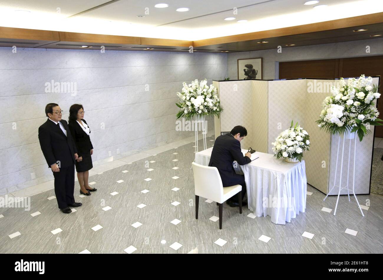Japan's Prime Minister Shinzo Abe signs a condolences book for the late Lee Kuan Yew, former Prime Minister of Singapore, as Singapore's ambassador Chin Siat Yoon and his wife Wang Lee Moi observe at the Singapore Embassy in Tokyo March 24, 2015. Lee, Singapore's first prime minister and architect of the tiny Southeast Asian city-state's rapid rise from British tropical outpost to global trade and financial centre, died early on Monday, aged 91, the Prime Minister's Office said. REUTERS/Eugene Hoshiko/Pool Stock Photo