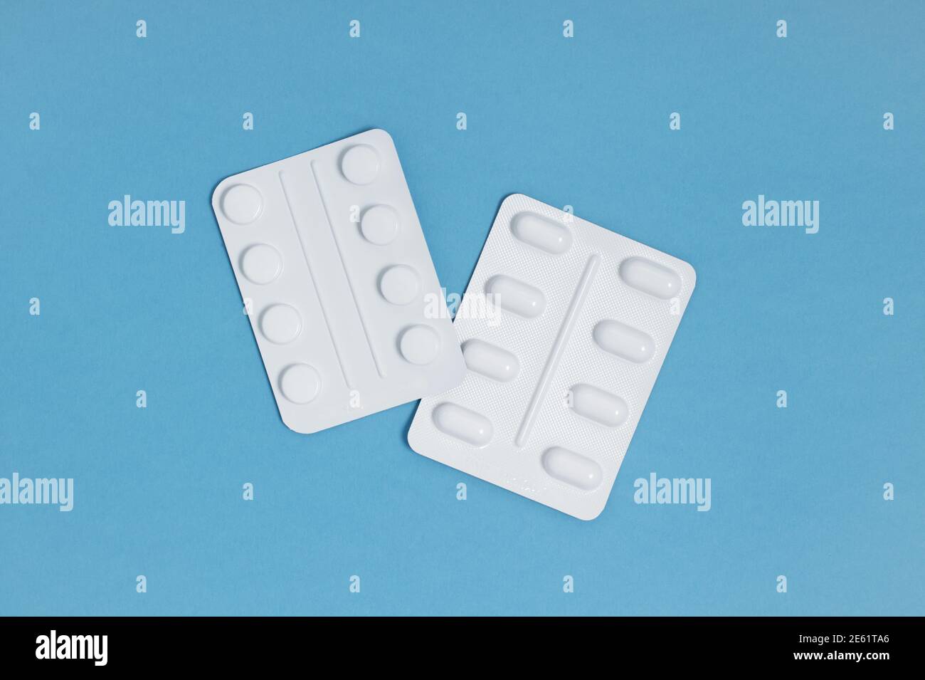 Two blister packs of tablets isolated on a bright blue background, overhead view Stock Photo