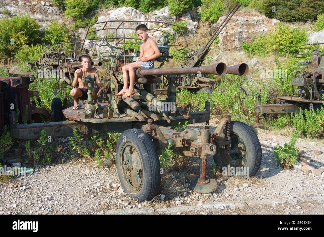Shengjin, Albania - July 27, 2012: two Albanian children are playing with a piece of rusty artillery the Second World War that i Stock Photo