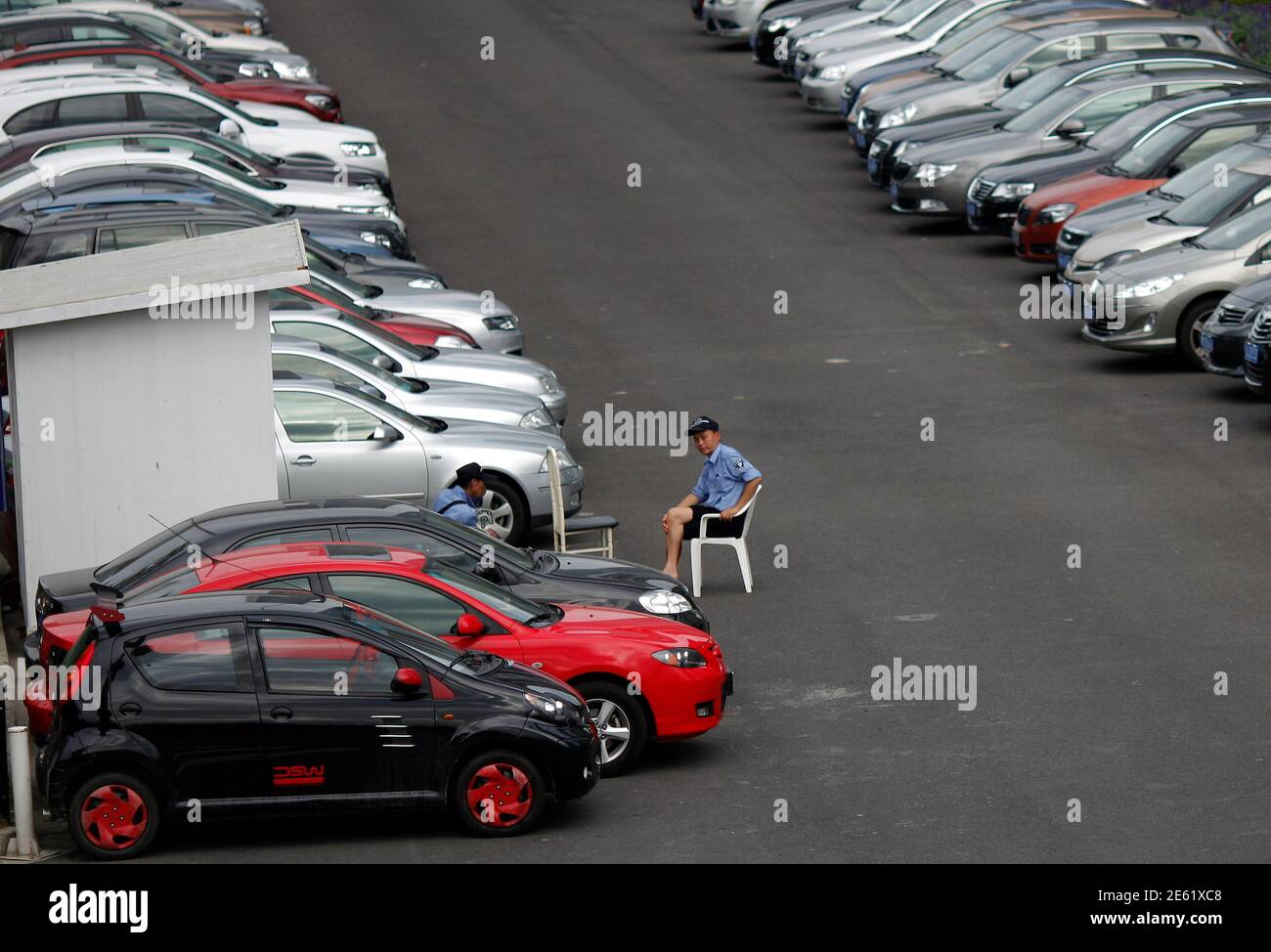 A parking lot guard sits on a chair in a downtown area of Shanghai June 5, 2012. While the opportunities are vast in China's estimated $50 billion auto insurance industry, there are roadblocks aplenty - from poor driving standards to a new generation of car owners unfamiliar with the concept of buying protection against accidents and repairs. In 2010, China reported 3.9 million road accidents that killed 65,225 people and injured 254,075. For comparison, there were 30,797 fatal crashes in the United States in 2009, according to the National Highway Traffic Safety Administration, which has almo Stock Photo