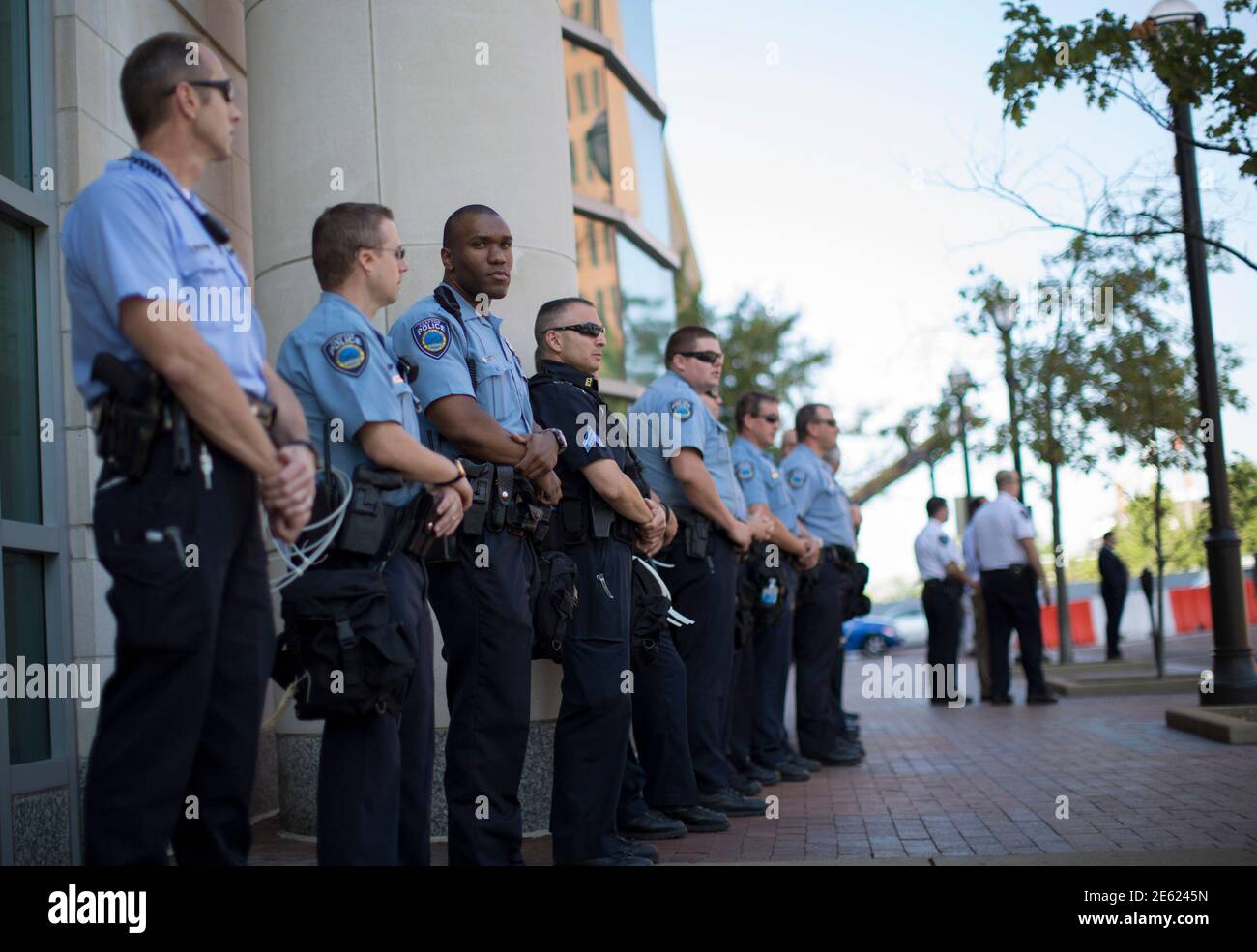 Police officers stand guard as demonstrators (not pictured) protest against the death of black teenager Michael Brown, outside St Louis County Circuit Clerk building in Clayton, Missouri August 12, 2014. Police said Brown, 18, was shot in a struggle with a gun in a police car but have not said why Brown was in the car. At least one shot was fired during the struggle and then the officer fired more shots before leaving the car, police said. But a witness to the shooting interviewed on local media has said that Brown had been putting his hands up to surrender when he was killed. The FBI has open Stock Photo