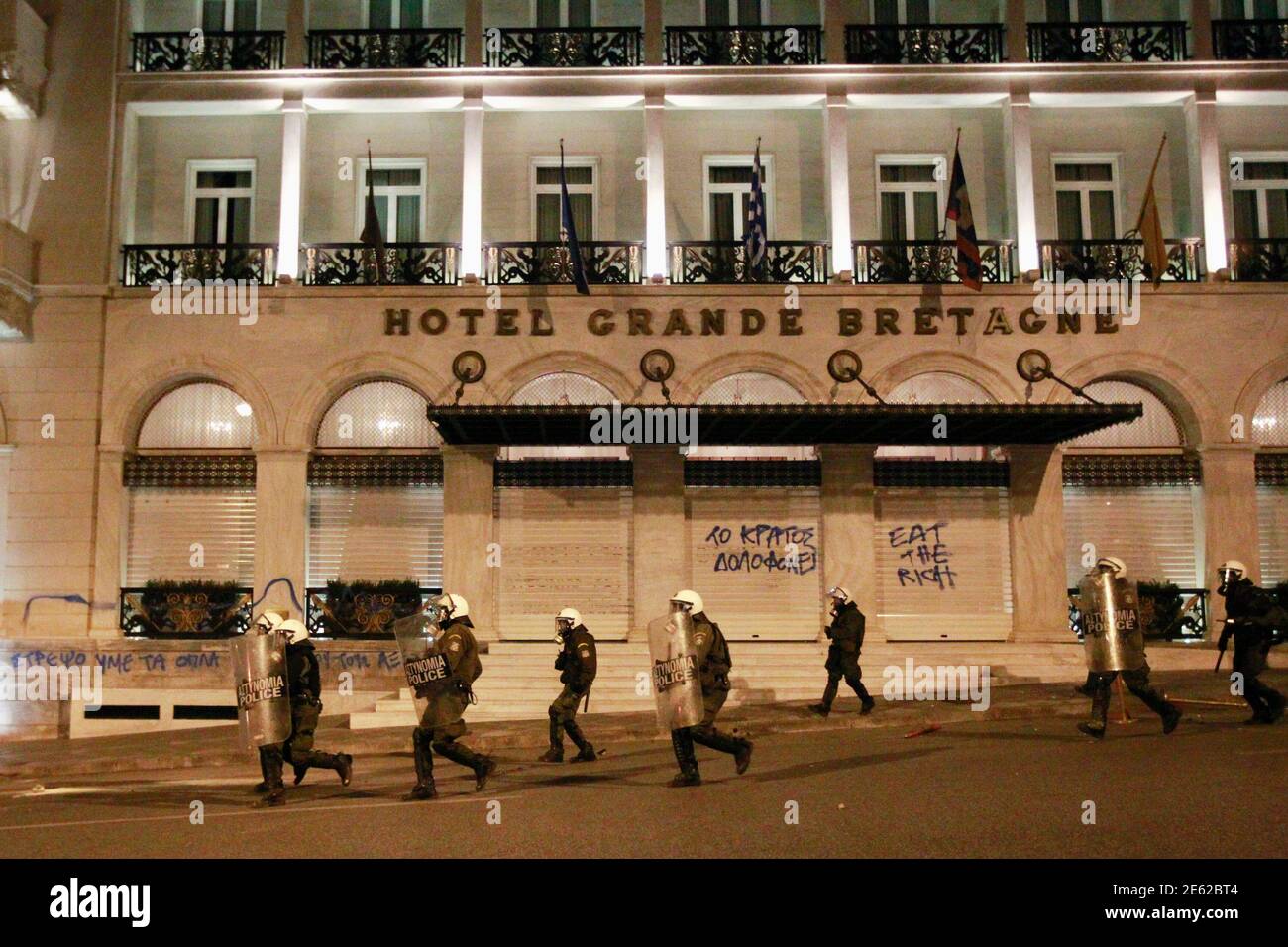 Policemen run in front of the entrance of Grande Bretagne hotel during riots at central Syntagma square in Athens April 4, 2012. Greek police fired teargas to disperse hundreds of protesters taking part in a rally commemorating the death of a Greek pensioner who shot and killed himself in Athens' parliament square on Wednesday after crying out to bystanders that crippling debts had pushed him to take his life. Suicides have risen in Greece as a deepening economic crisis leaves one in five jobless and countless more struggling to survive on sharply reduced salaries and pensions.    REUTERS/John Stock Photo