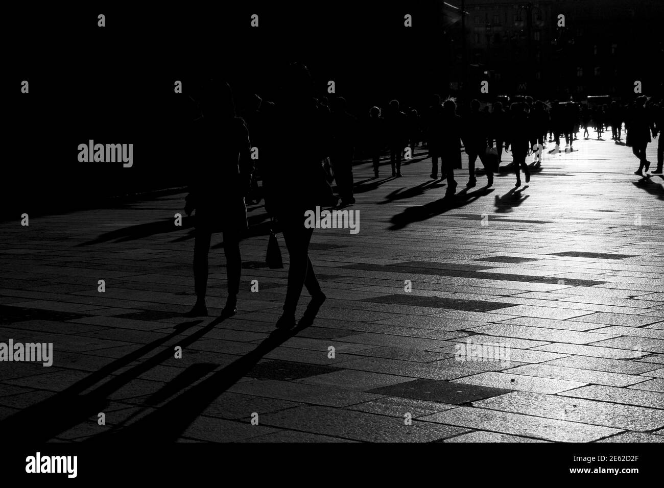 Shadows of people walking at sunset on the stone floor of the pre-pandemic city of Milan, Lombardy, Italy Stock Photo