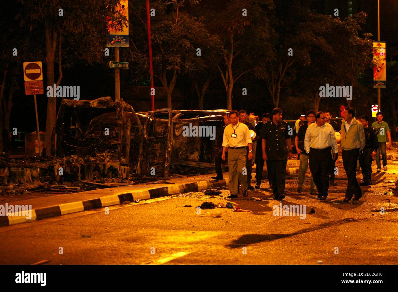 Singapore's Deputy Prime Minister Teo Chee Hean (front R) and Minister in  Prime Minister's Office S Iswaran (front 2nd R) look at the site of two  burnt vehicles following a riot in