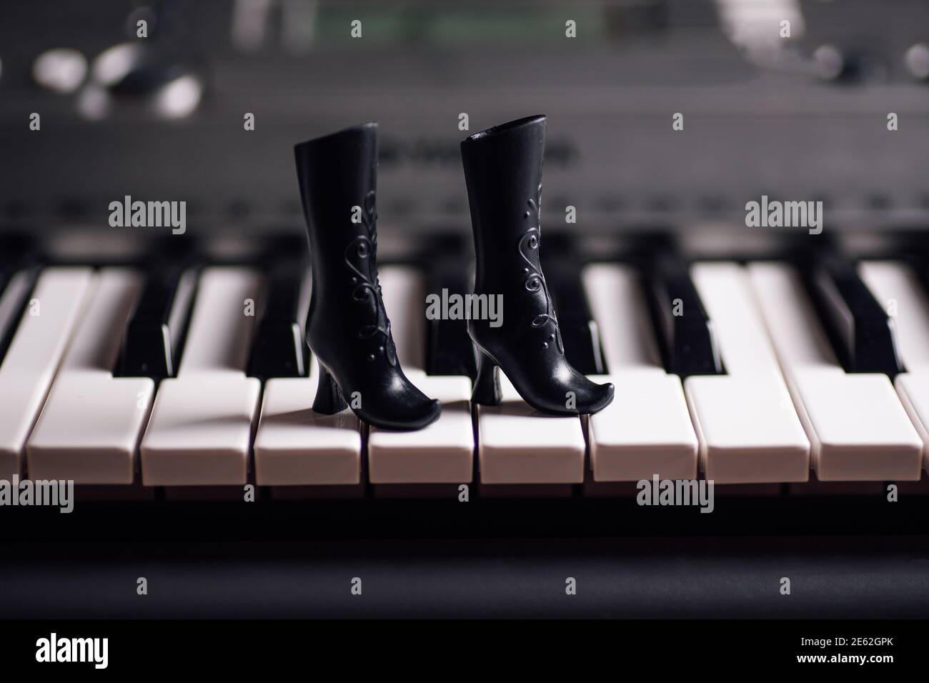 close-up black toy rubber boots with high heels on piano keys Stock Photo