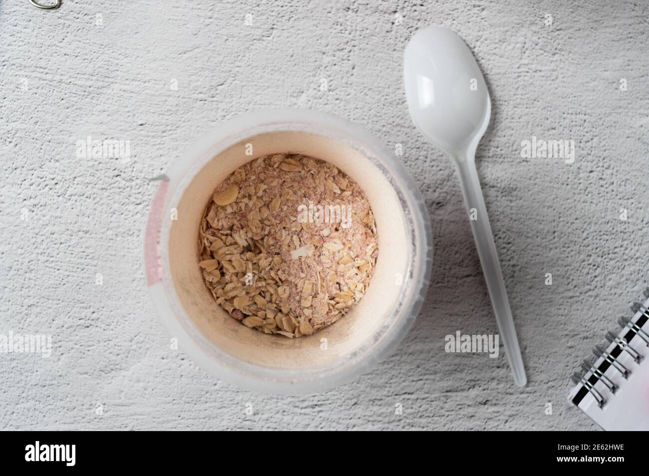 Dry oatmeal. Oatmeal in a glass. Oatmeal and plastic spoon. Stock Photo
