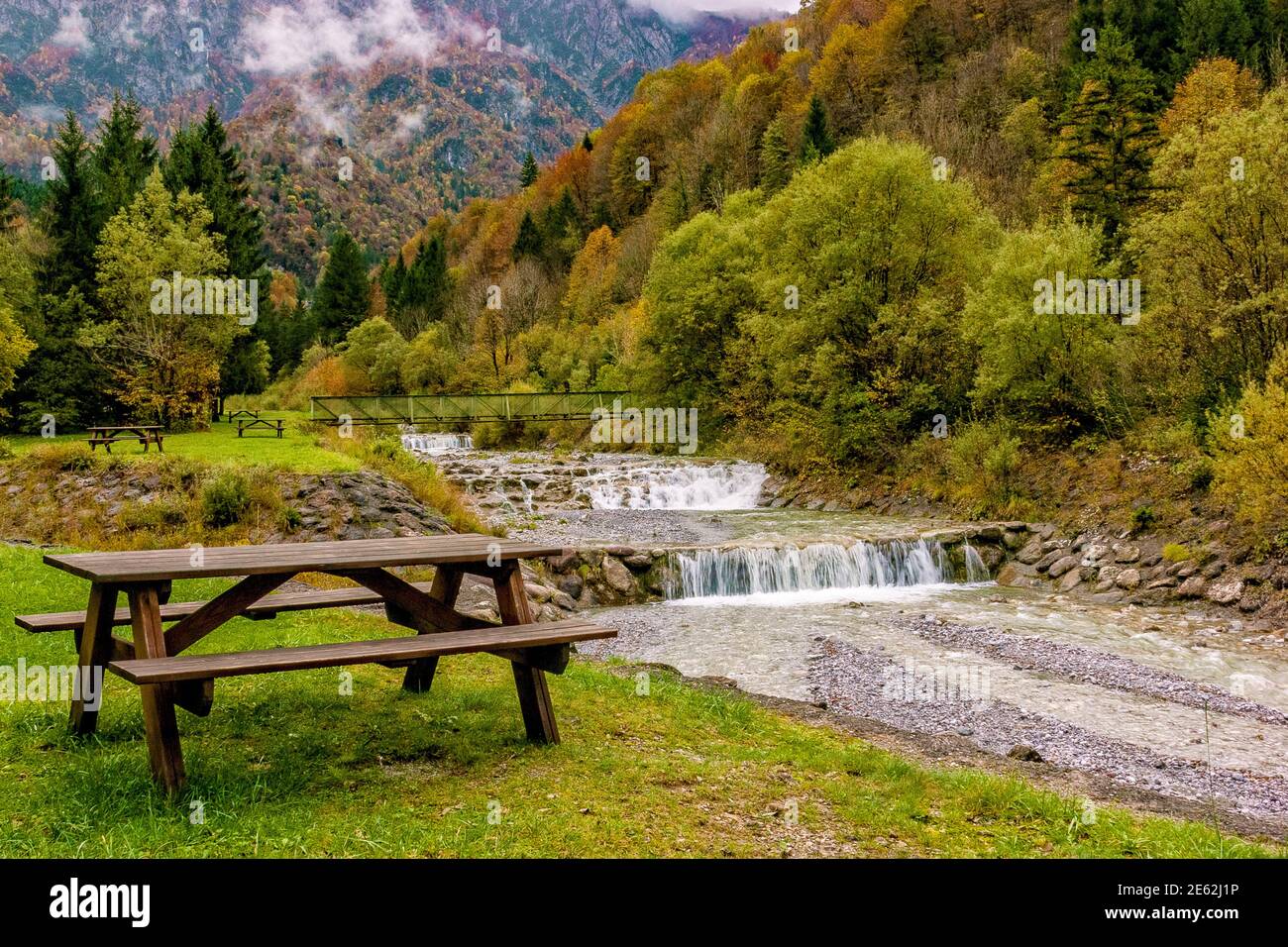Picnic table in autumn on the banks of a mountain stream Stock Photo