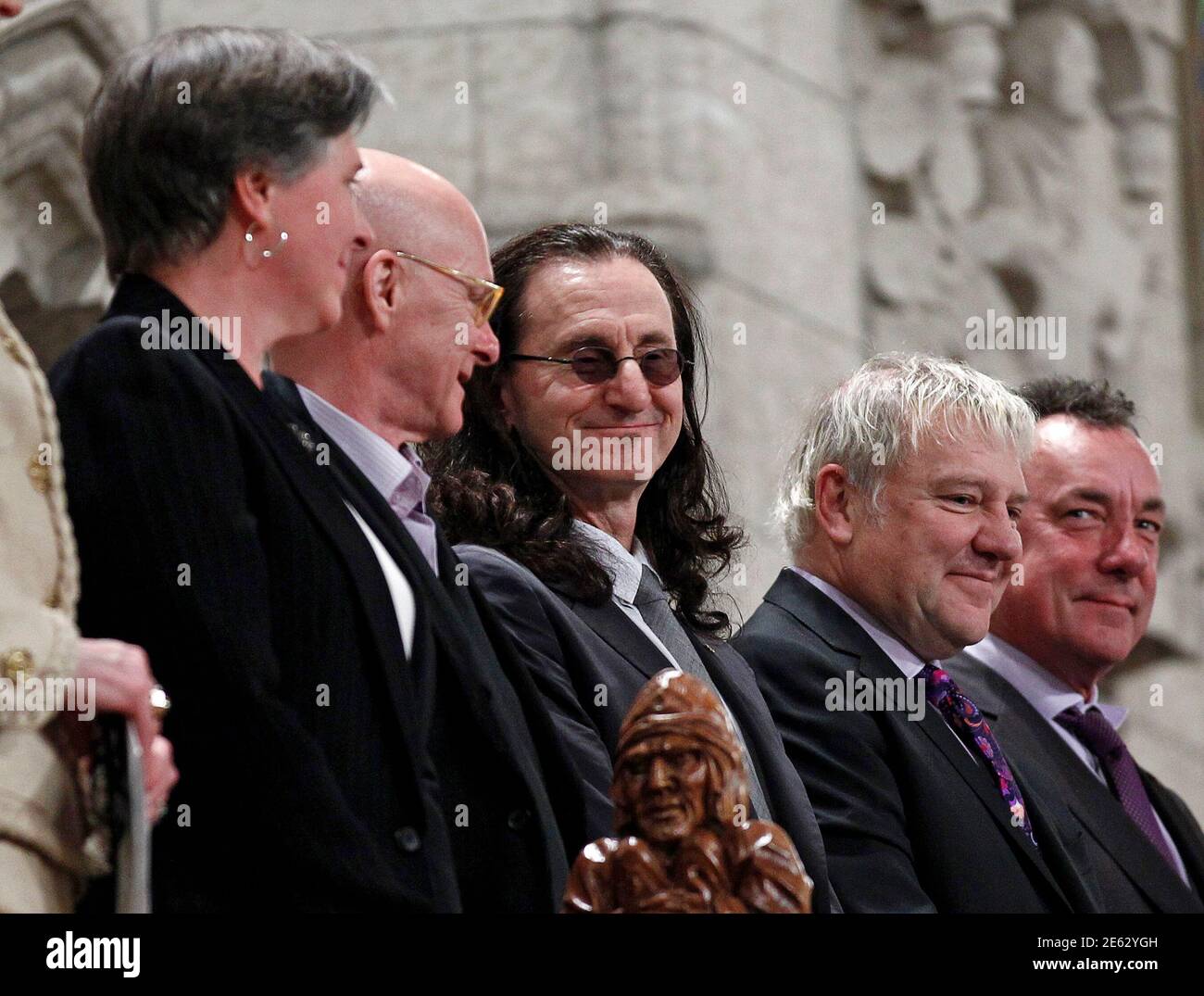 Geddy Lee (C), Alex Lifeson (2nd R) and Neil Peart (R) of the Canadian rock band Rush smile while being recognized along with fellow recipients of the Governor General's Performing Arts Awards in the House of Commons on Parliament Hill in Ottawa May 3, 2012. Also pictured are Janina Fialkowska (L) and Paul-Andre Fortier.       REUTERS/Chris Wattie       (CANADA - Tags: POLITICS ENTERTAINMENT) Stock Photo
