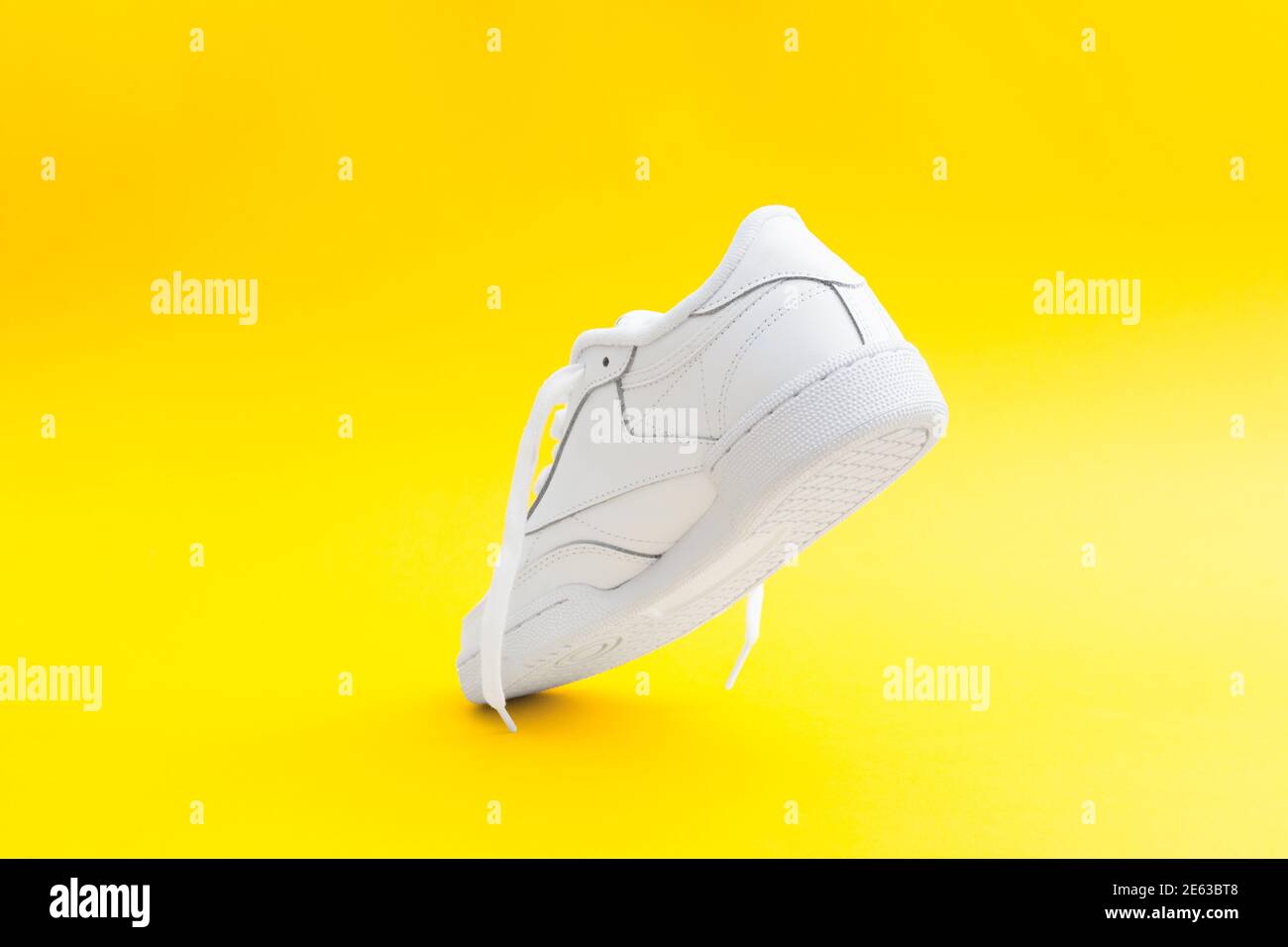 Women's stylish white sneaker on yellow background Heel counter of sport shoe Stock Photo