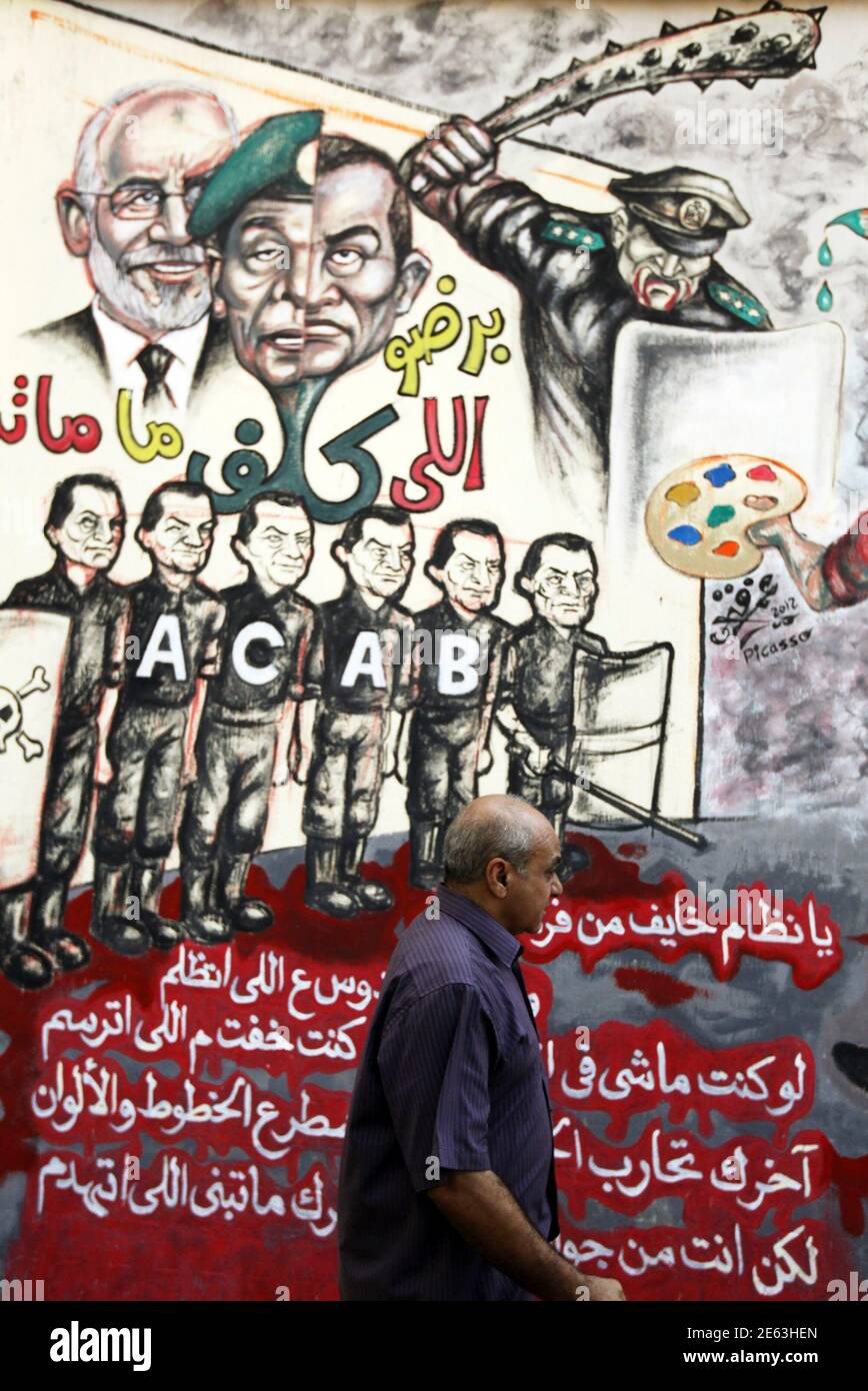 A Man Walks Past A Graffiti Of Egypt S Former President Hosni Mubarak Former Field Marshal Mohamed Hussein Tantawi And Muslim Brotherhood Leader Mohamed Badie Along Mohamed Mahmoud Street Near Tahrir Square In