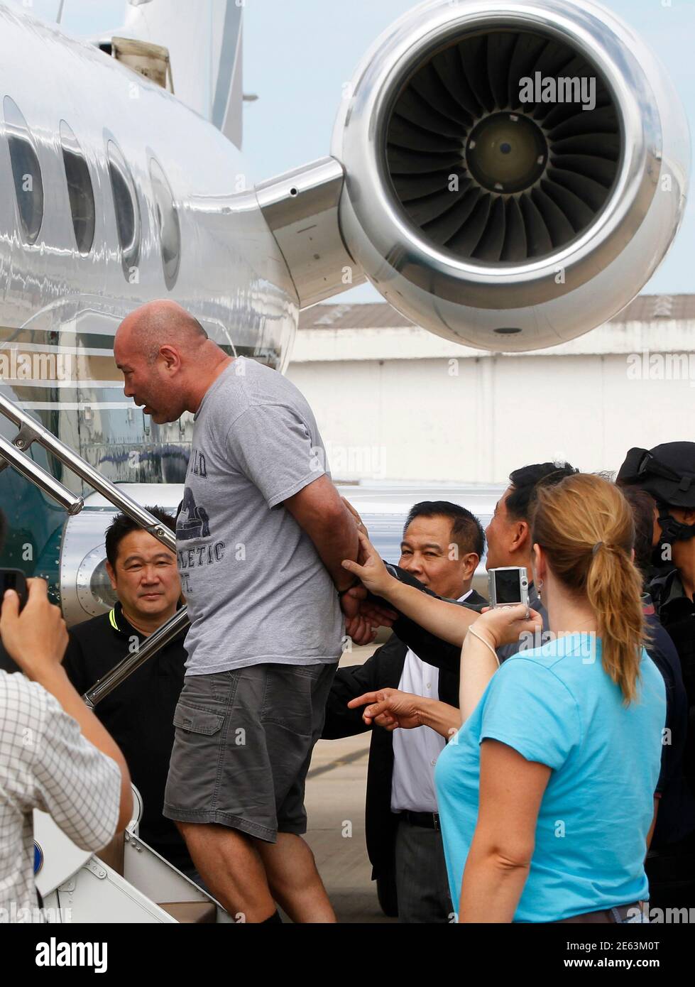 Thai policemen escort American drug suspect Joseph Hunter, 48, as he boards a charter flight at Don Mueang International Airport in Bangkok September 27, 2013. Thai police transferred six foreigners suspected of drug smuggling to Bangkok on Thursday after their arrests in the seaside resort, Phuket. Hunter, along with two British, a Taiwanese, a Slovak, and a Filipino were arrested on Phuket island on Wednesday following a tip-off from the United States Drug Enforcement Administration (DEA). REUTERS/Chaiwat Subprasom (THAILAND - Tags: CRIME LAW DRUGS SOCIETY) Stock Photo