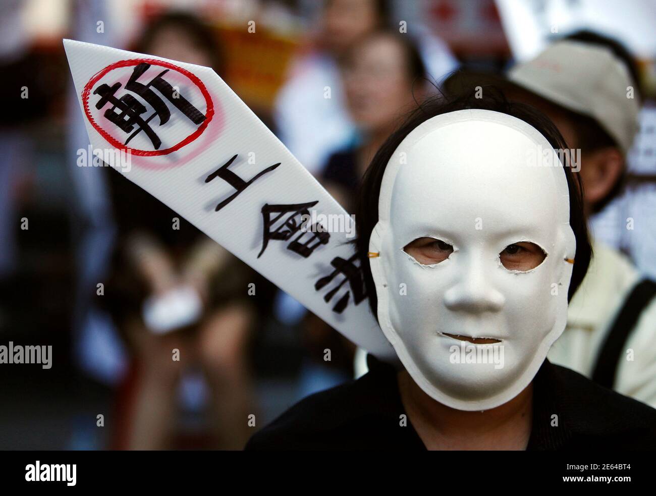A employee wears a mask during a protest against Nan Shan Life, which is the Taiwan unit of AIG, outside their building headquarters in Taipei September 28, 2010. The protesters claim that the company is restricting employees' rights to freedom of speech by discouraging against the discussion of company matters with the media. AIG is sure of at least one bidder for its Taiwan Nan Shan Life unit should it put it back on the market, with Chinatrust Financial reaffirming its interest on September 21 after the original buyers pulled out. The words on the board read 'Cutting away the worker's union Stock Photo
