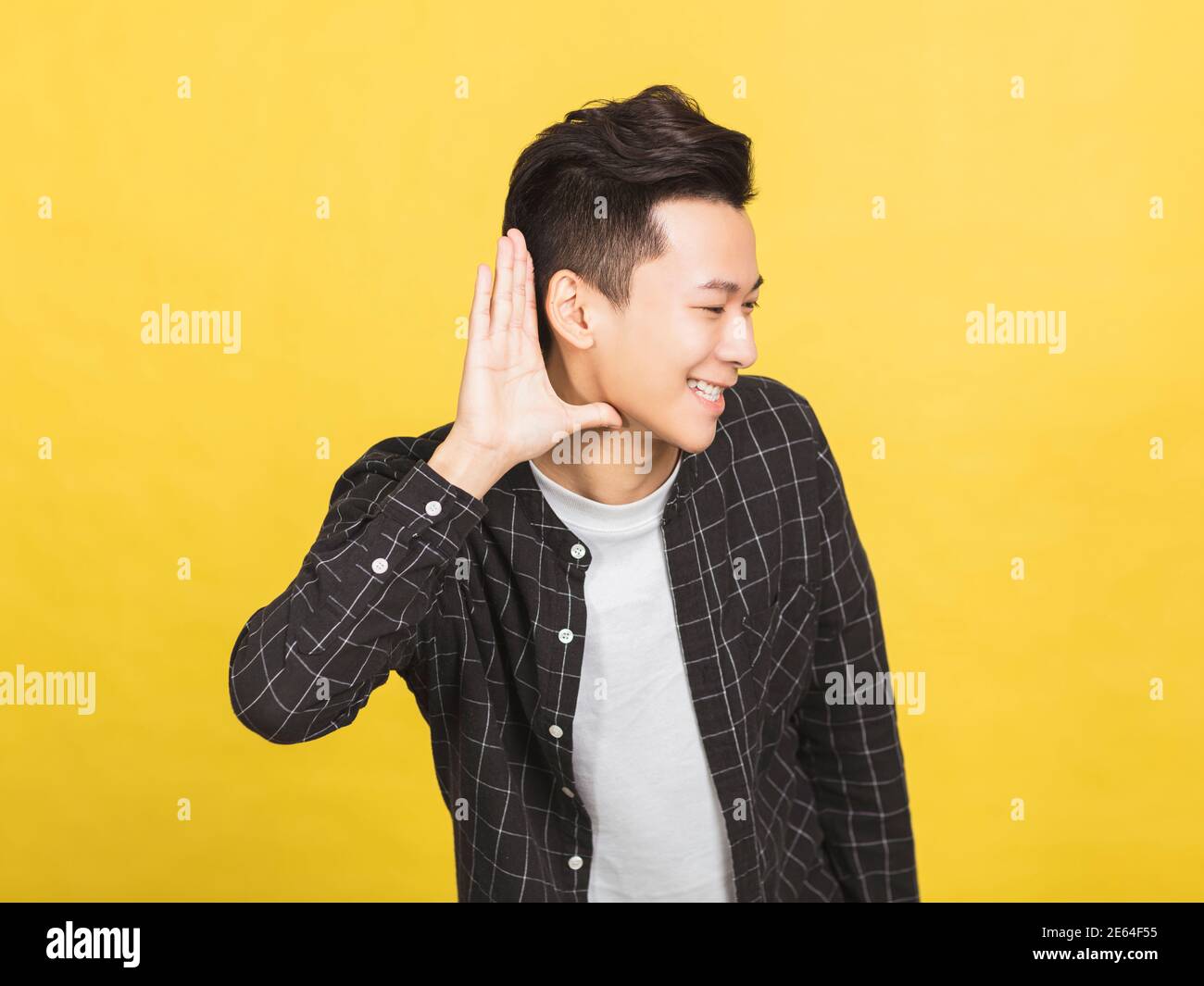 smiling young man hand over ear listening an hearing to rumor or gossip Stock Photo
