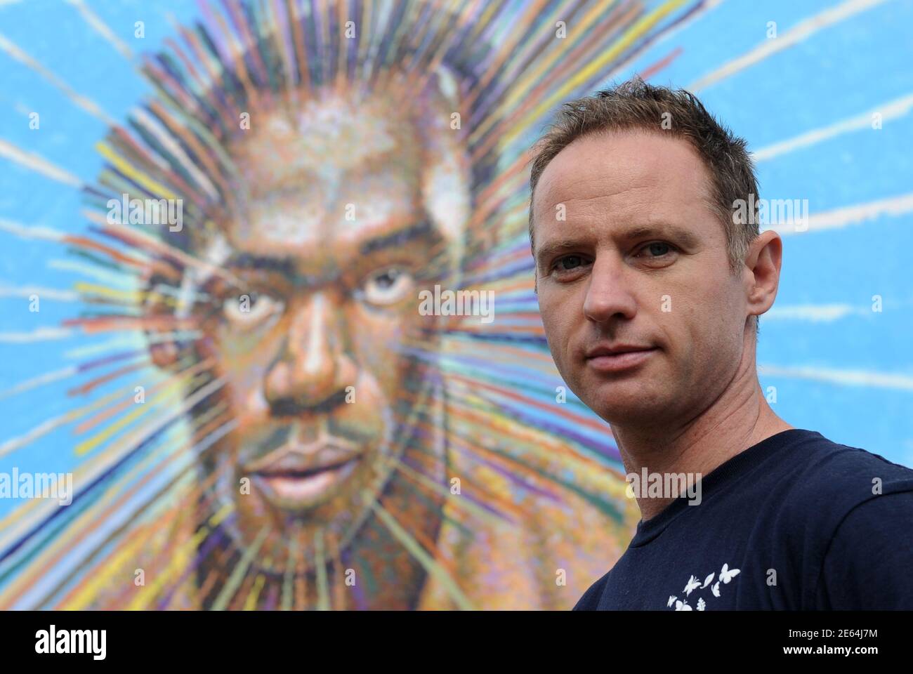 Street artist James Cochran, also known as Jimmy C, poses near his spray painted picture of Jamaican sprinter Usain Bolt in Sclater street car park in east London July 19, 2012. Cochran said this was done as an homage to the London 2012 Olympic Games, which begin July 27. REUTERS/Paul Hackett  (BRITAIN - Tags: SPORT OLYMPICS ATHLETICS ENTERTAINMENT) Stock Photo