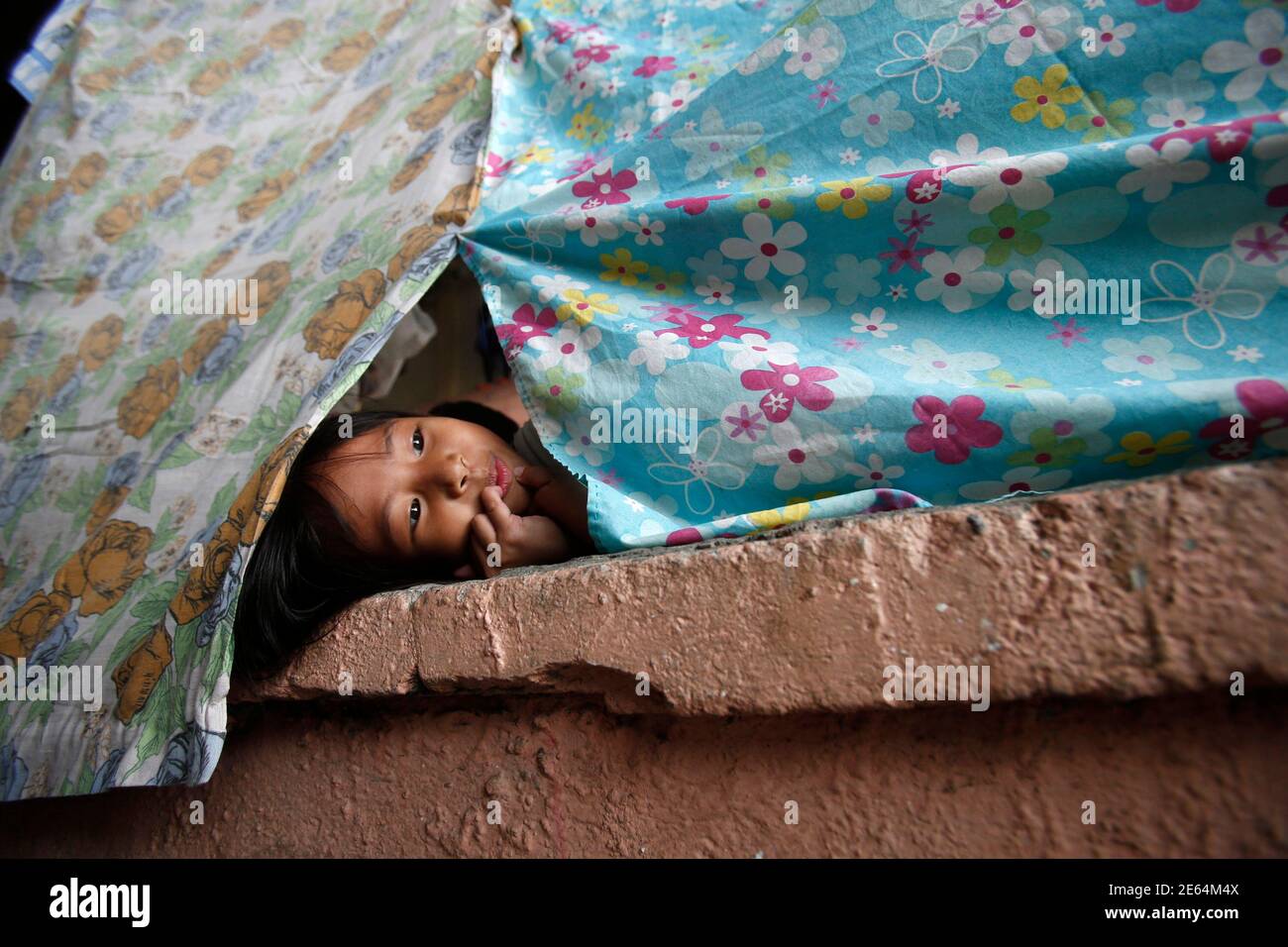 A girl looks out from a makeshift tent at an evacuation centre for flood victims in Calumpit, Bulacan, north of Manila, August 22, 2013. The southwest monsoon that wreaked havoc on Metro Manila and nearby areas earlier this week is likely to weaken now that Typhoon Trami made landfall over China, state weather forecasters said Thursday. The death toll from the heavy monsoon rain and floods since last weekend rose to at least 16 as of Thursday morning, the National Disaster Risk Reduction and Management Council said. REUTERS/Erik De Castro (PHILIPPINES - Tags: DISASTER ENVIRONMENT) Stock Photo