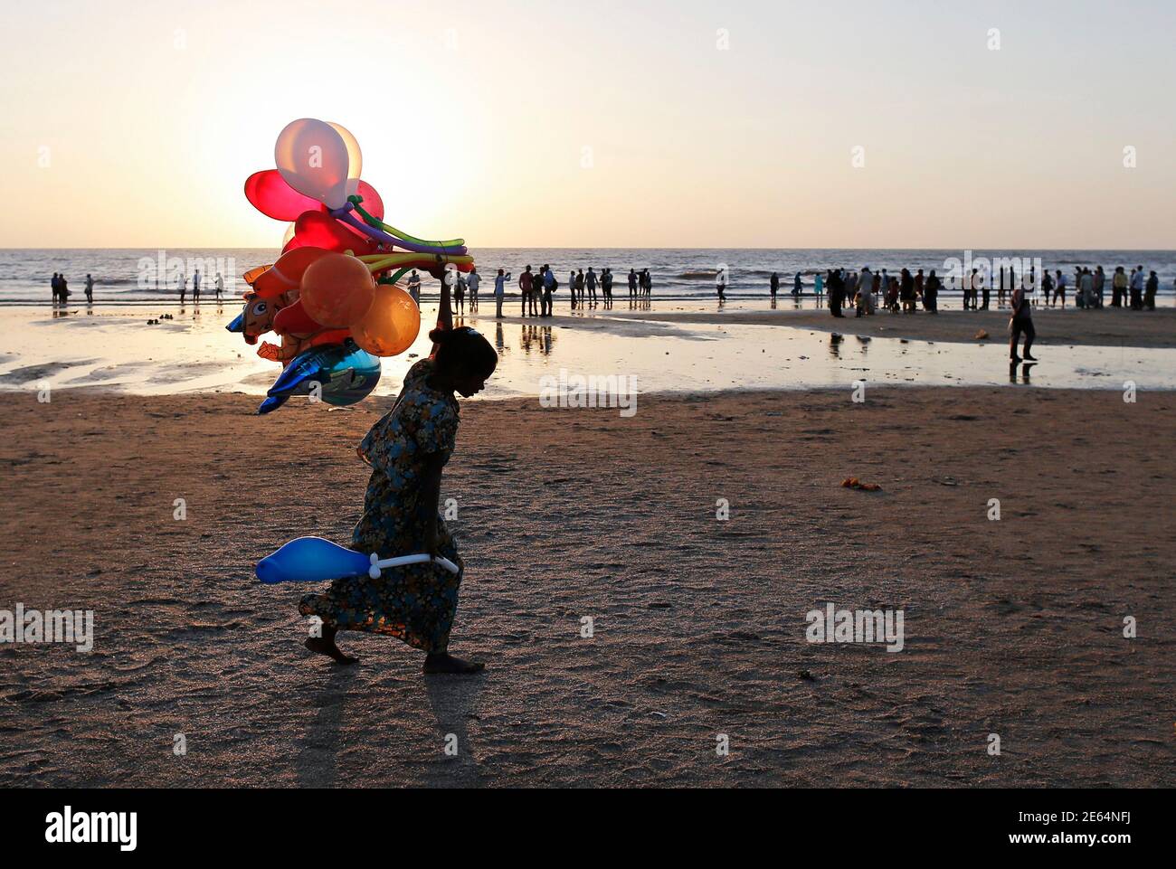 Meera, 9, is silhouetted against the setting sun while selling balloons along the shores of the Arabian Sea in Mumbai February 11, 2014. REUTERS/Danish Siddiqui (INDIA - Tags: SOCIETY) Stock Photo
