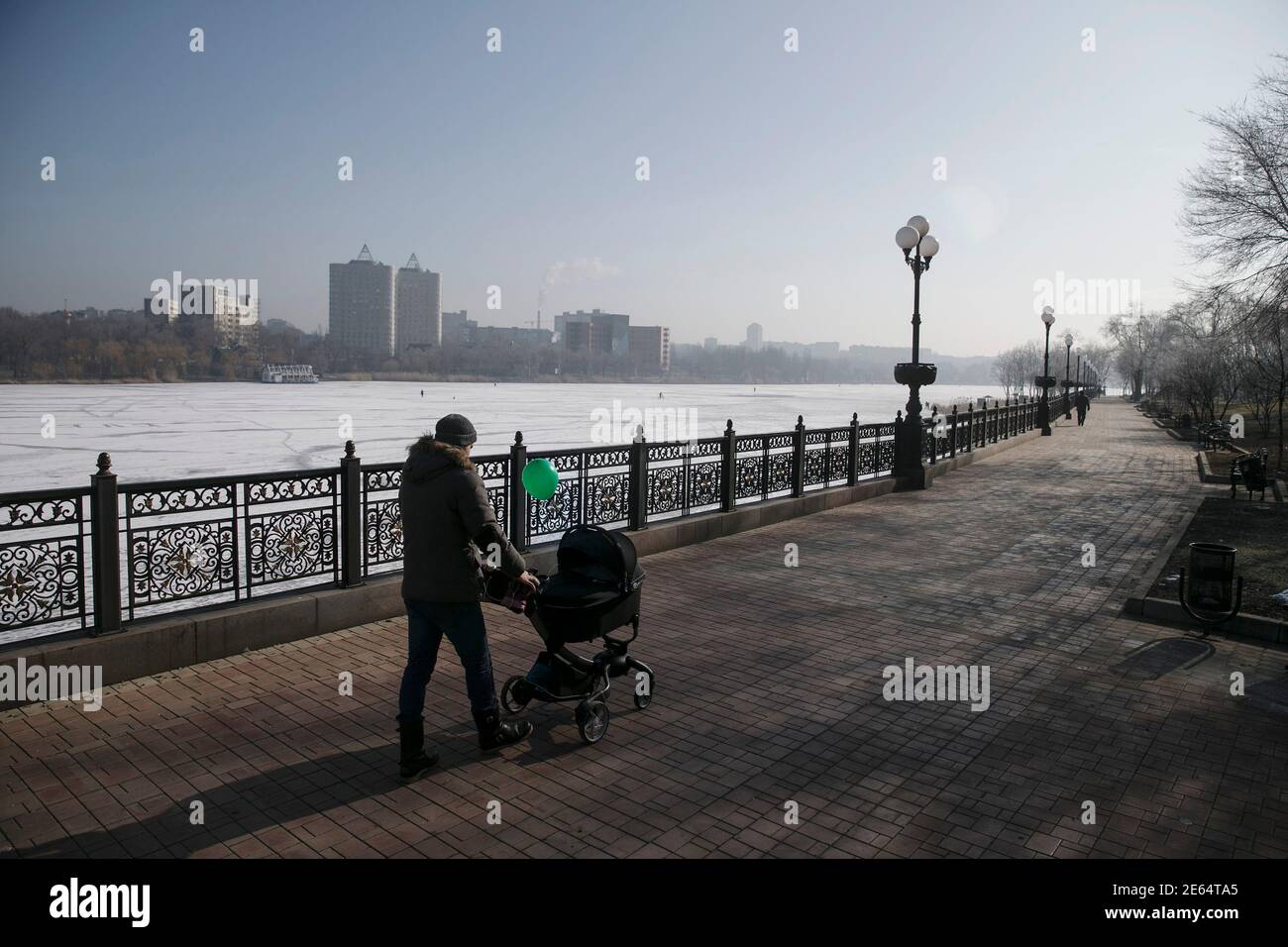 A man pushes a stroller near a frozen river in Donetsk, February 15, 2015. The Ukrainian military said on Sunday a ceasefire between government troops and pro-Russian separatists in east Ukraine is being observed 'in general' and that rebel attacks are infrequent and not widespread . REUTERS/Baz Ratner (UKRAINE - Tags: CIVIL UNREST POLITICS CONFLICT SOCIETY) Stock Photo