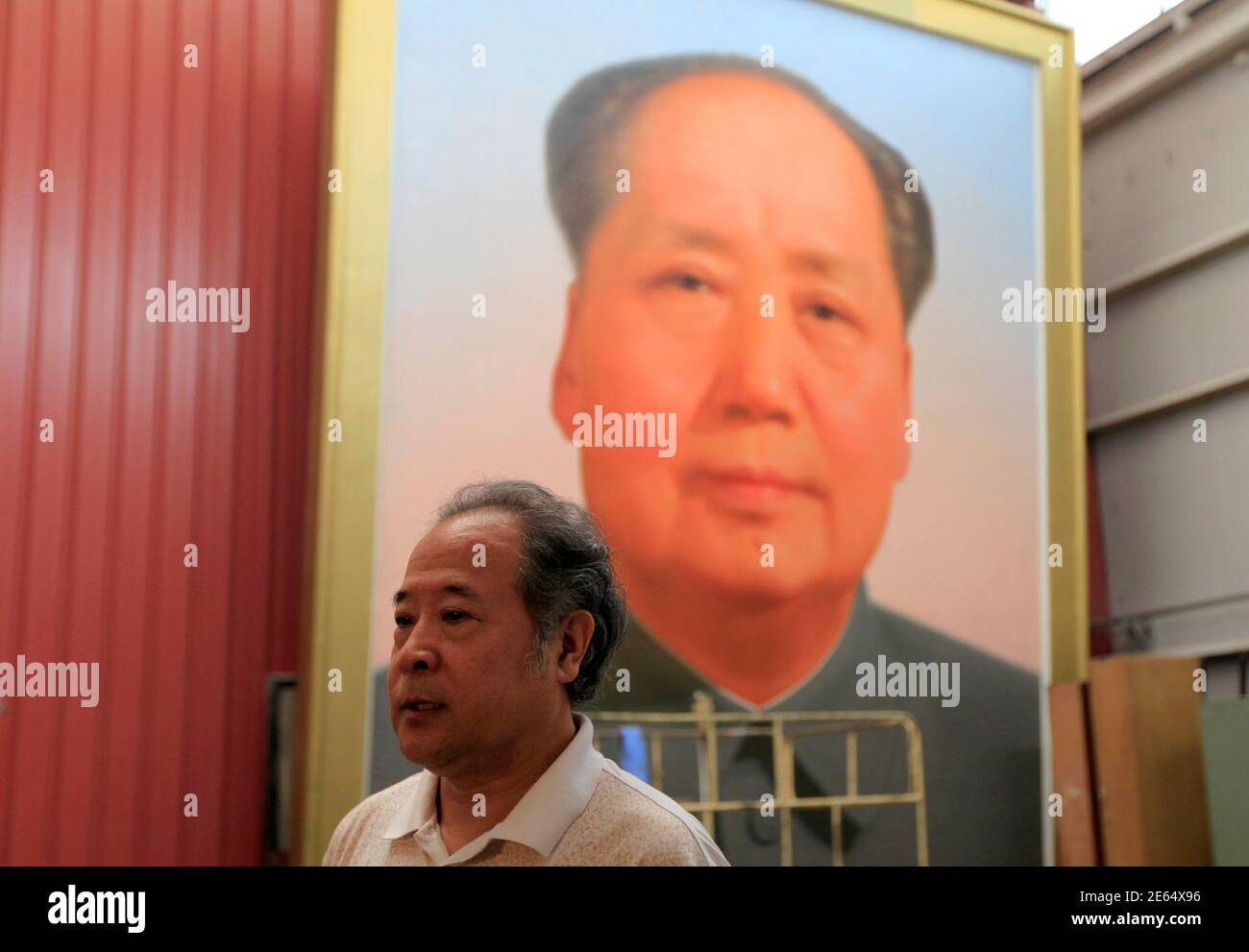 Ge Xiaoguang speaks in front of a giant portrait of China's late Chairman Mao Zedong during a interview with Reuters in his working studio located between the Tiananmen Square and the Forbidden City in Beijing June 29, 2011. Reclusive Chinese painter Ge's art has gazed over one of the world's most famous city squares for decades. For 30 years, he has painted the portraits of former paramount leader Mao Zedong that look across Beijing's Tiananmen Square. The giant oil paintings of the "Great Helmsman" have kept watch from the Gate of Heavenly Peace since the Communist Party won the civil war an Stock Photo
